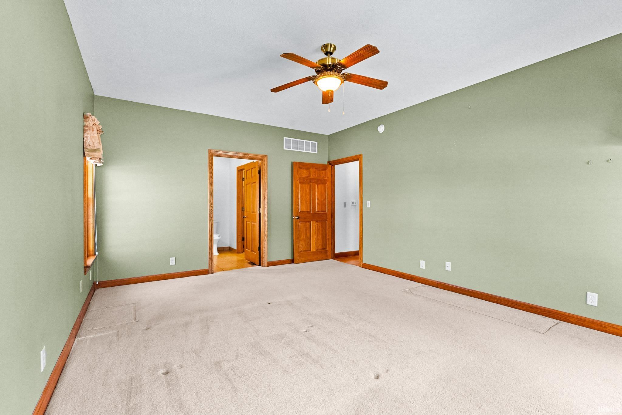 Unfurnished bedroom with carpet floors, a ceiling fan, and ensuite bathroom