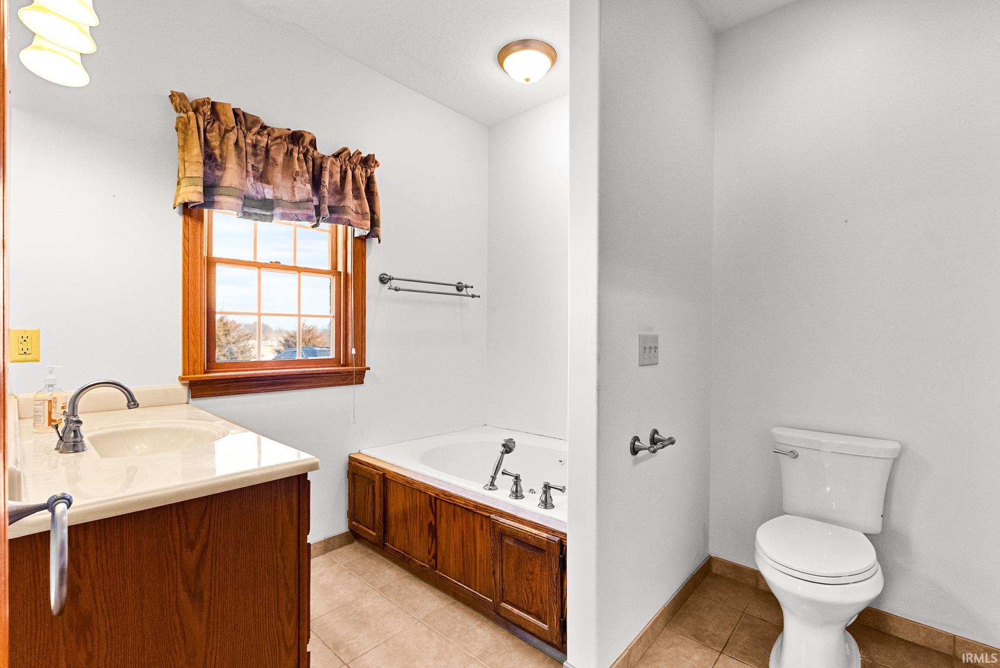 Bathroom featuring a bath, vanity, and light tile patterned floors