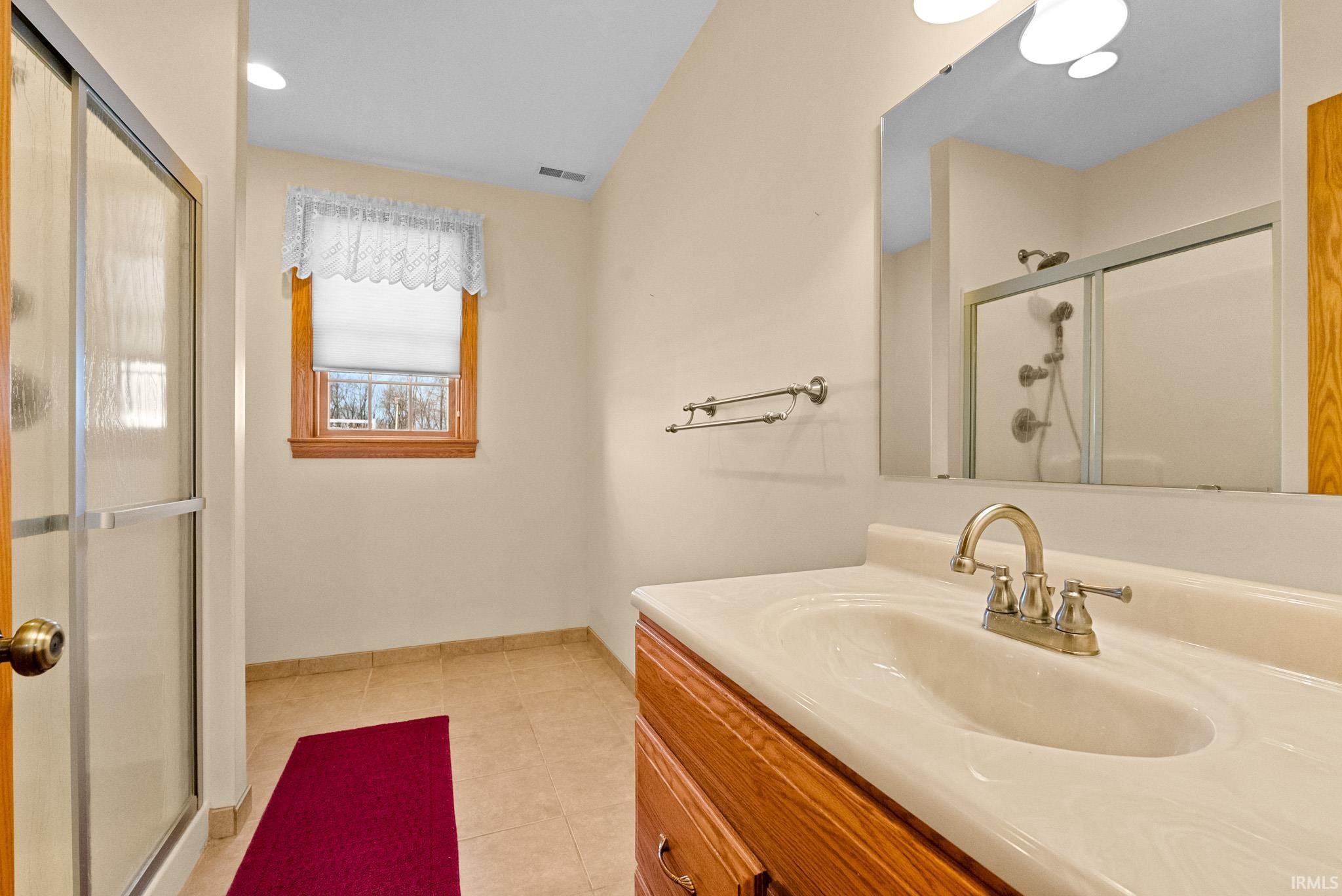 Bathroom featuring vanity, a shower stall, light tile patterned floors, and recessed lighting