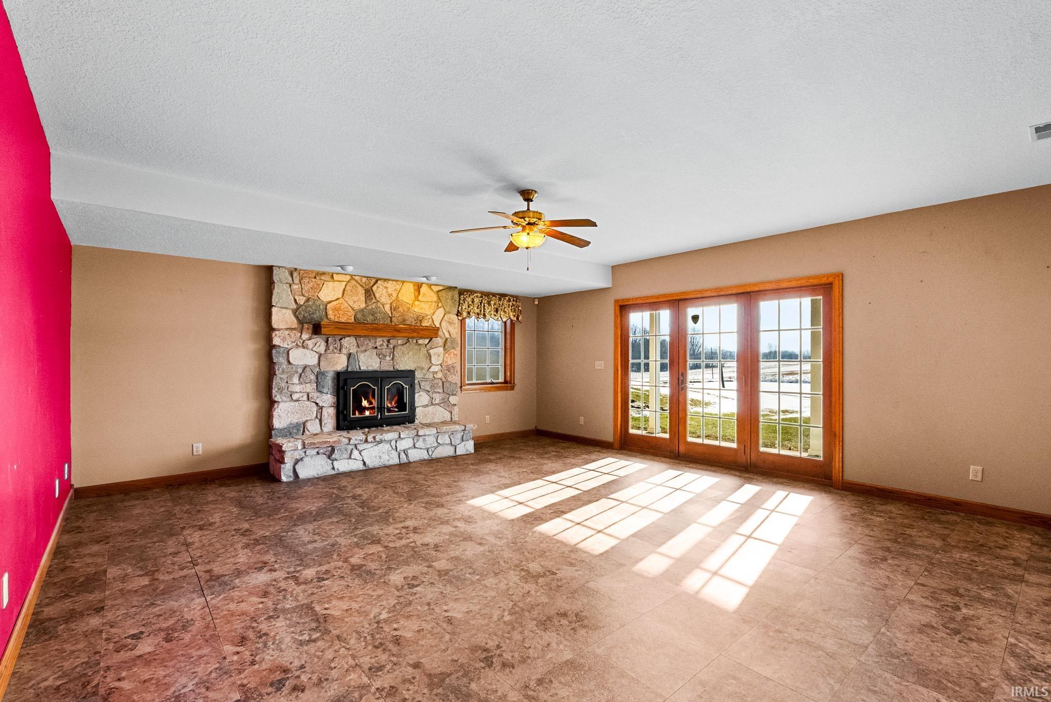 Unfurnished living room with healthy amount of natural light, a fireplace, ceiling fan, and a textured ceiling