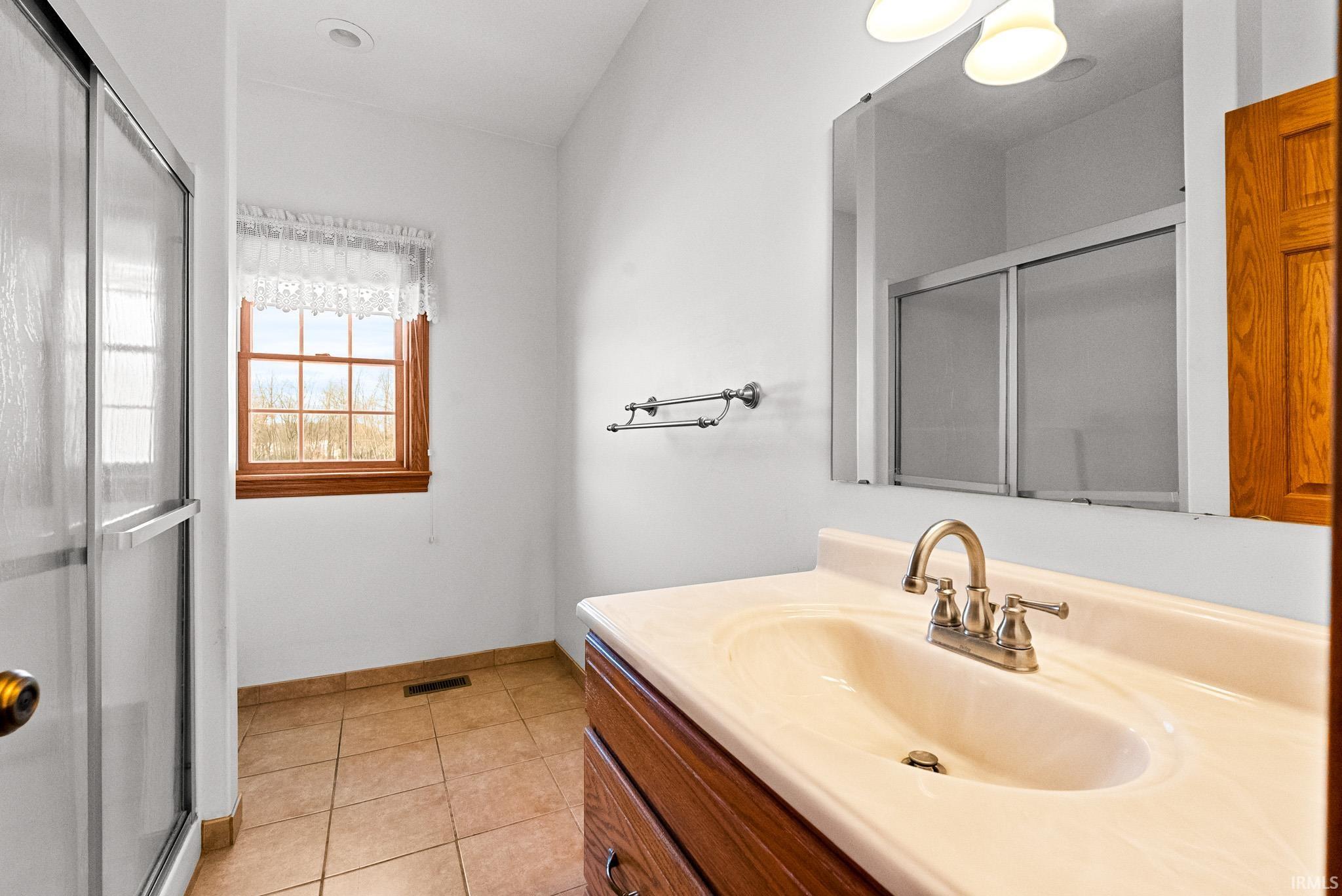 Full bathroom with vanity, a shower stall, and light tile patterned floors