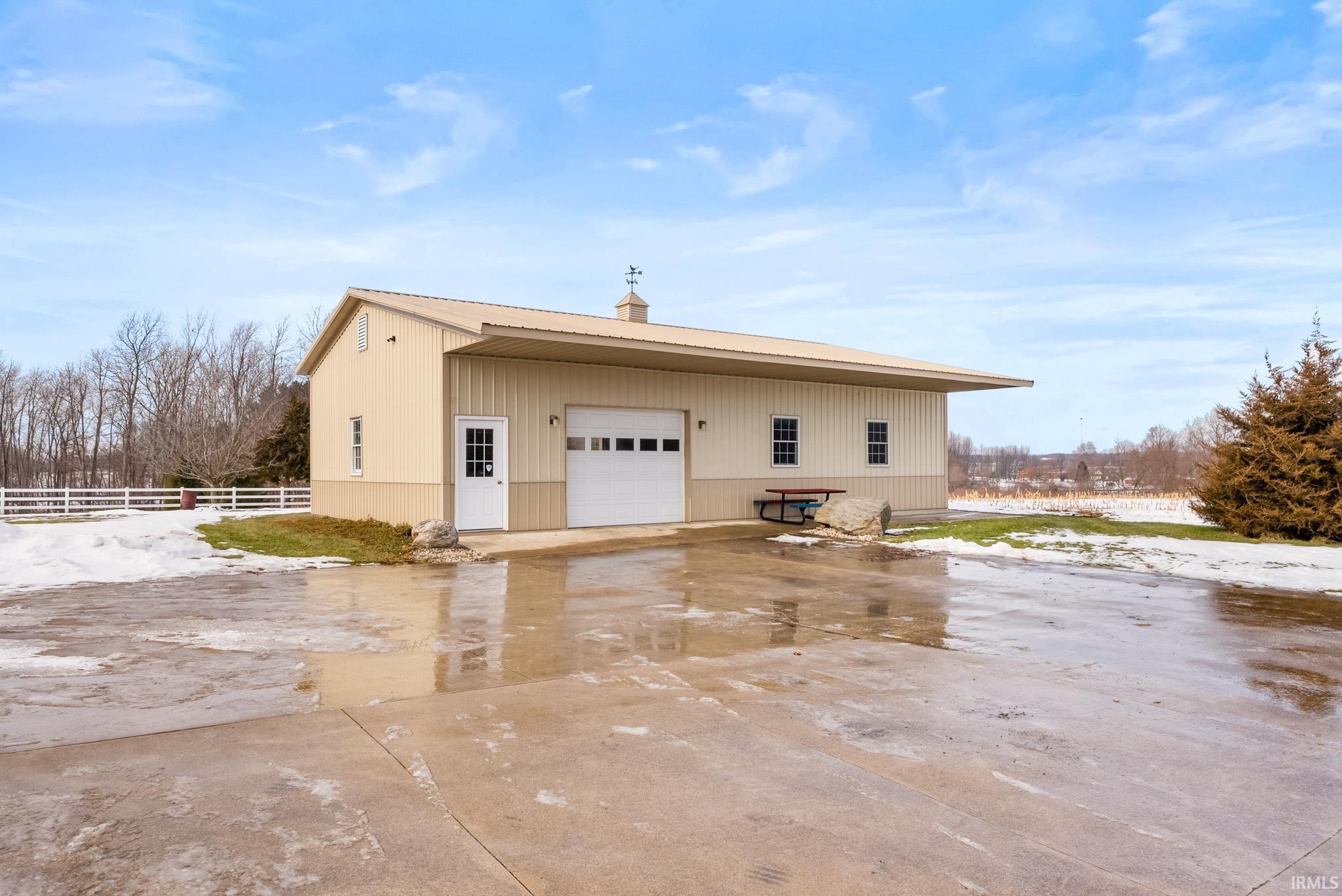 View of property exterior with a garage, an outdoor structure, a chimney, and driveway