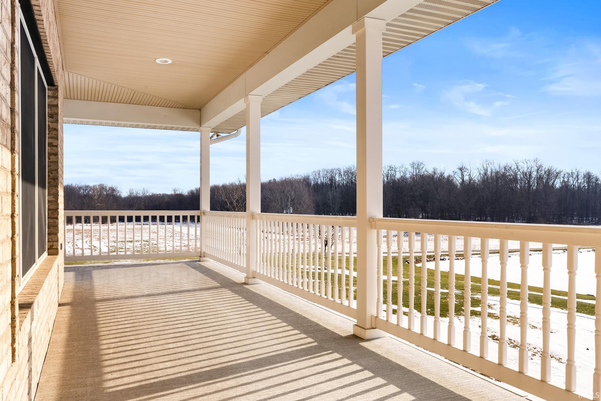 Wooden terrace featuring a view of trees and a patio area
