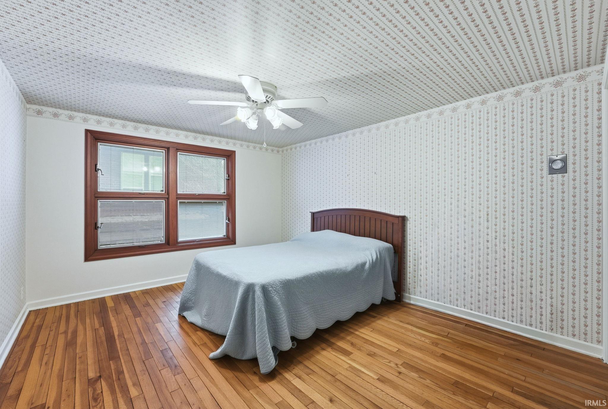 Bedroom featuring wallpapered walls, wood-type flooring, and ceiling fan