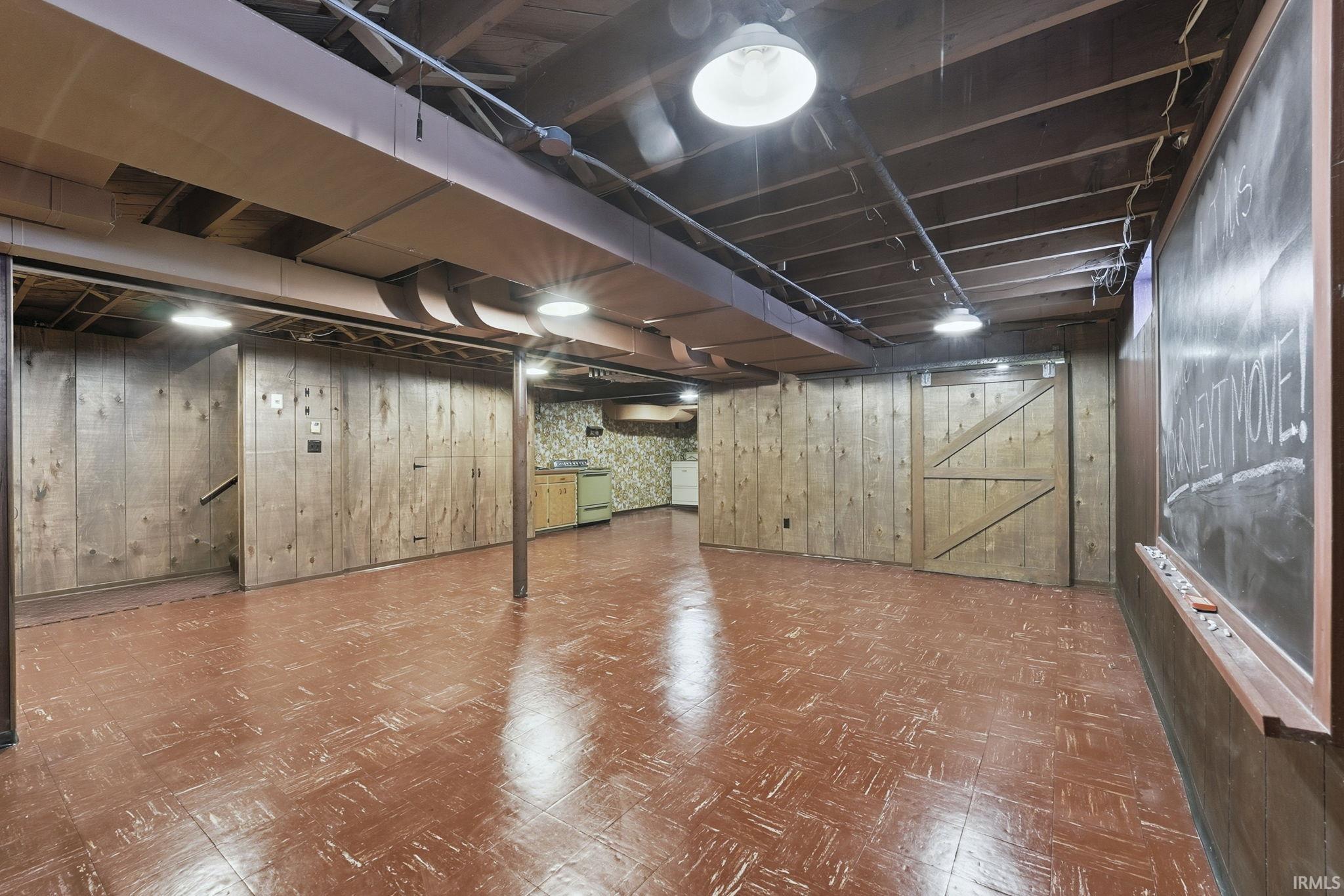 Finished basement featuring tile patterned floors, wooden walls, and a barn door