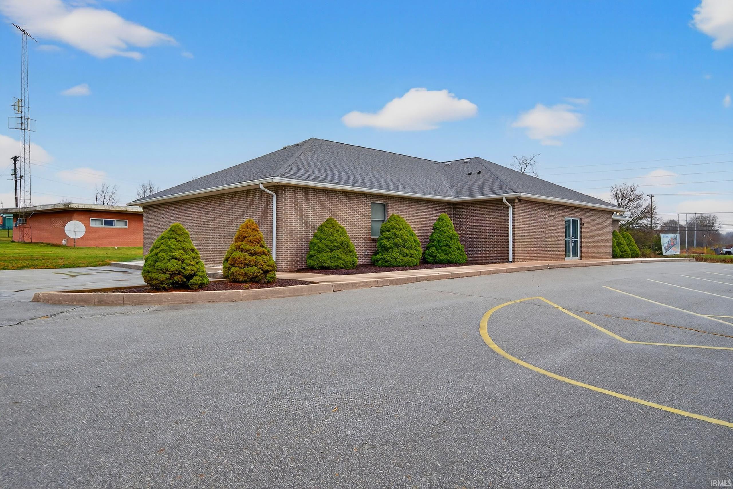 View of property exterior with brick siding and a shingled roof