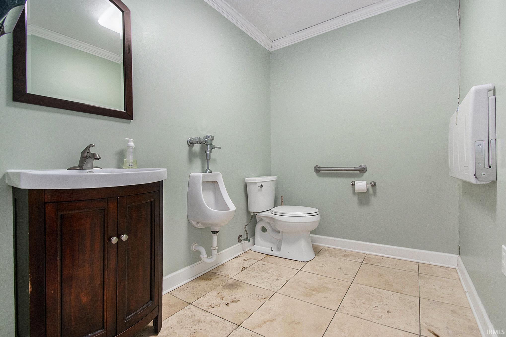 Half bathroom featuring ornamental molding, vanity, and light tile patterned floors