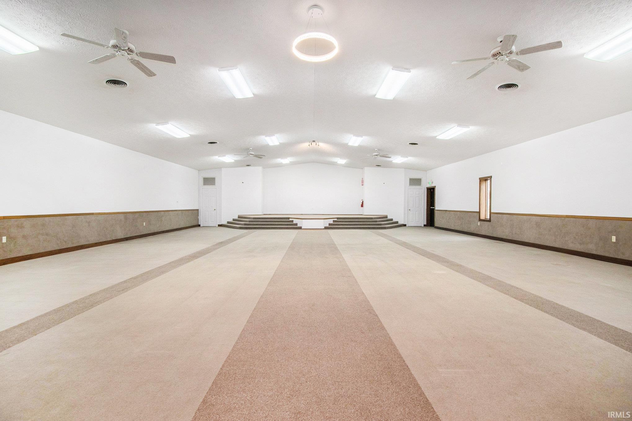 Misc room with ceiling fan, a wainscoted wall, and vaulted ceiling