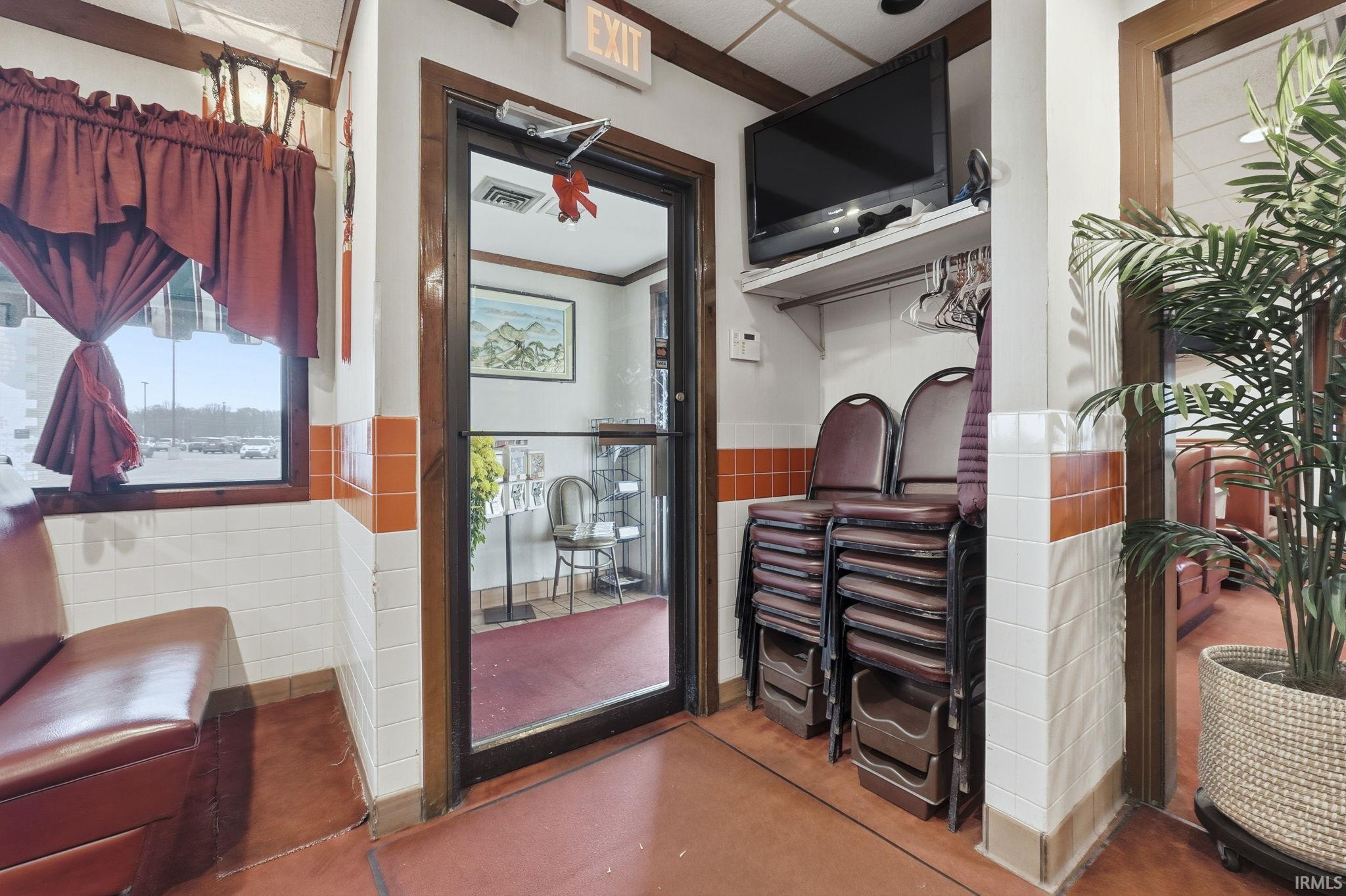 Hallway with wainscoting, concrete floors, tile walls, and crown molding