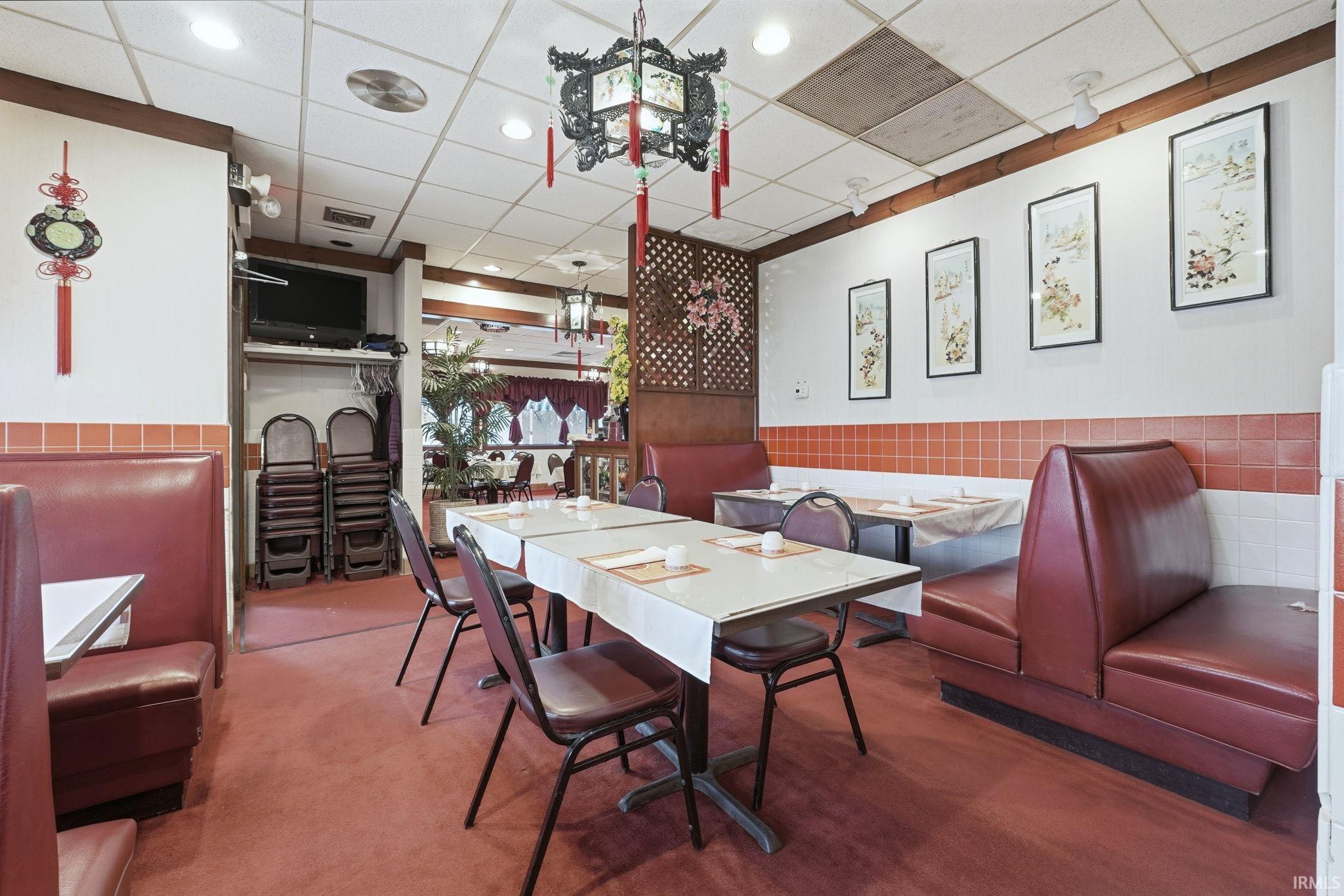 Dining space featuring carpet, a paneled ceiling, and wainscoting