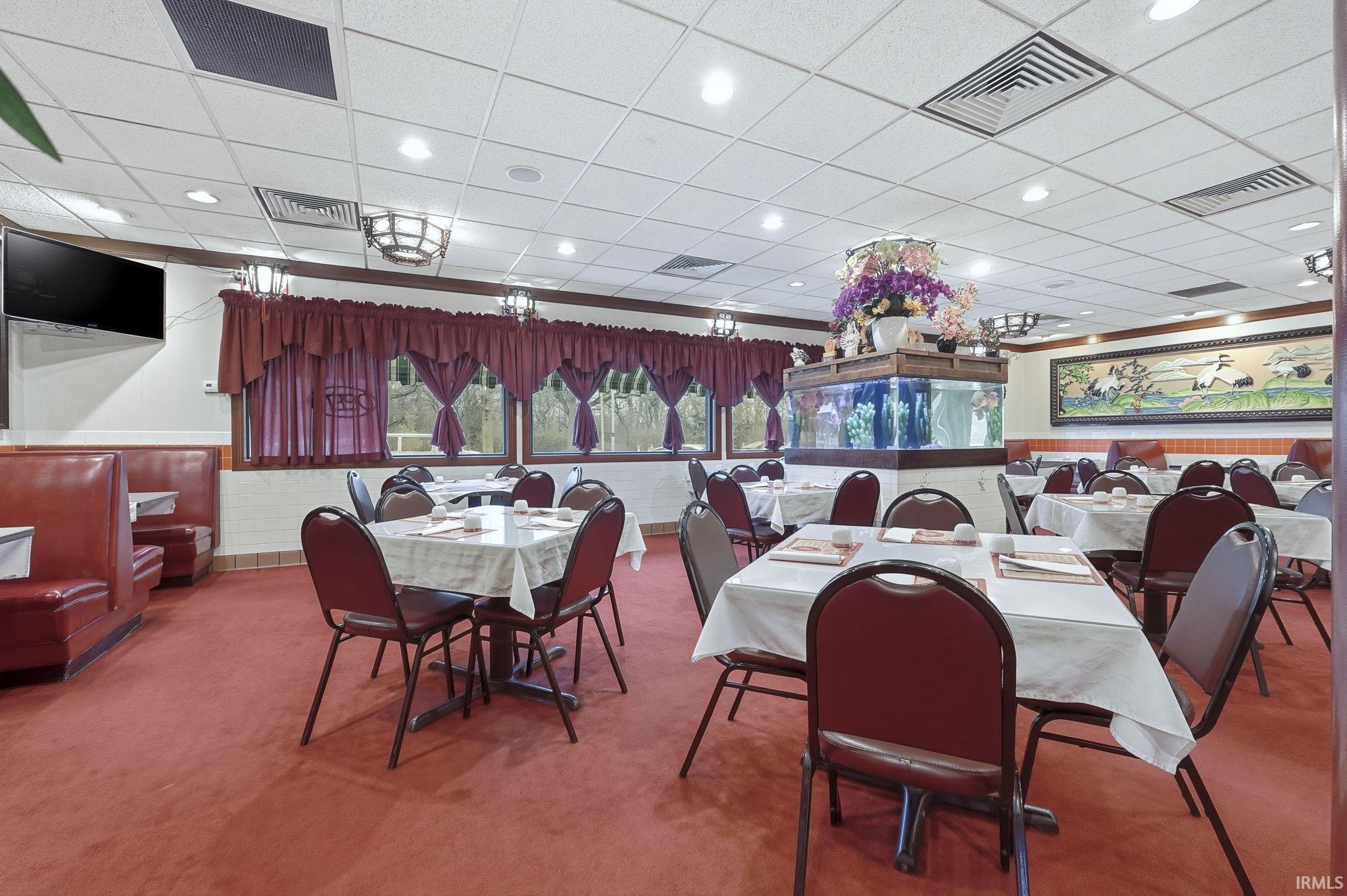 Carpeted dining room with wainscoting, a paneled ceiling, and recessed lighting
