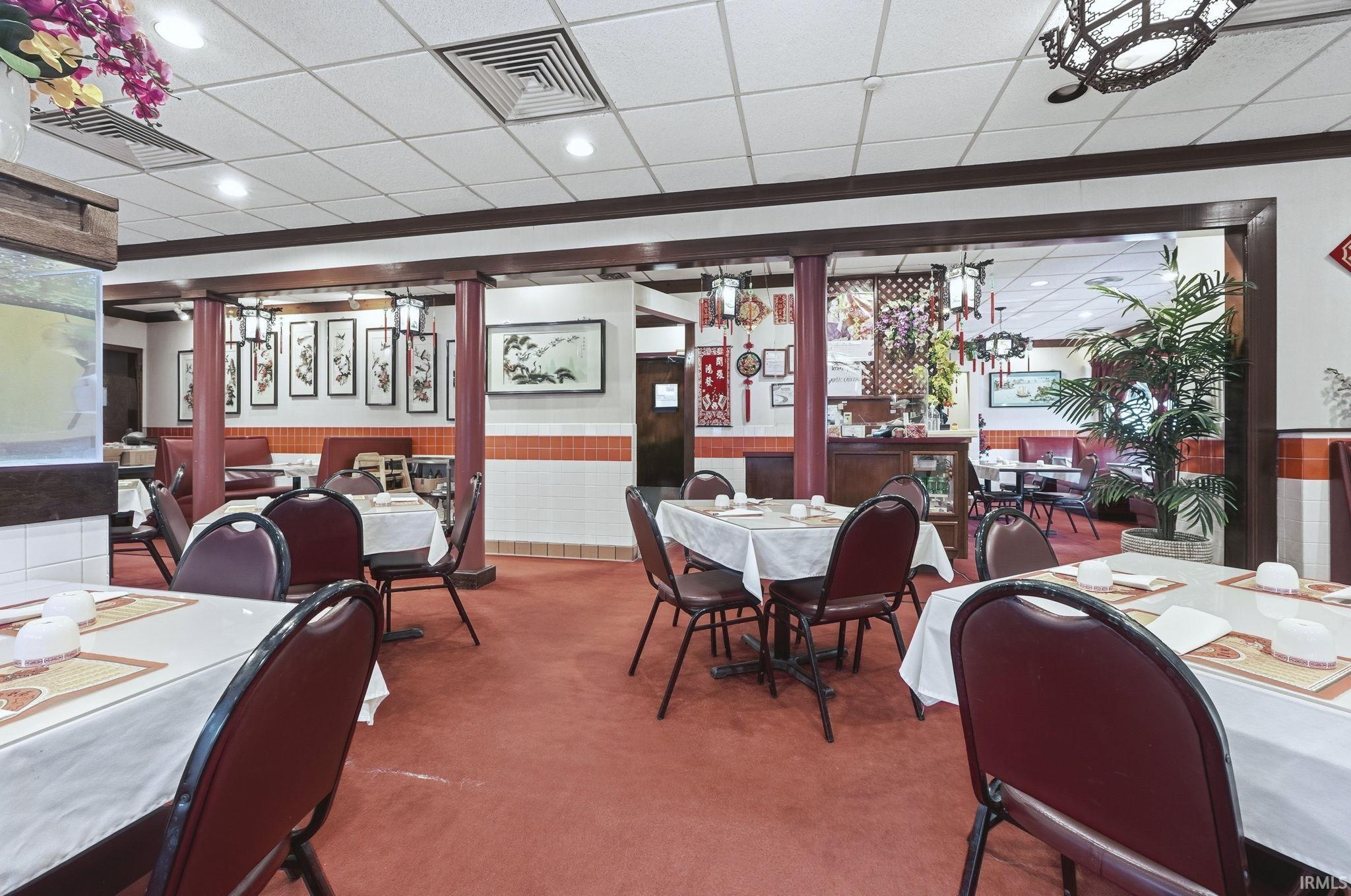 Dining room featuring a wainscoted wall, a paneled ceiling, and carpet