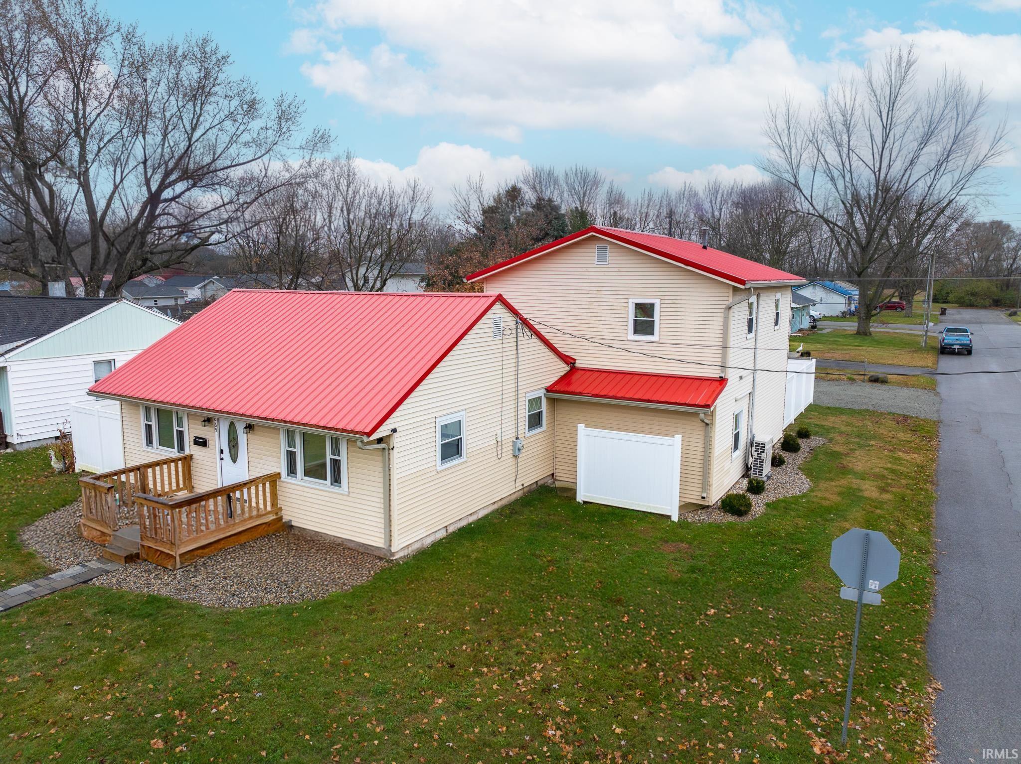 Rear view of house featuring a metal roof, a lawn, and a wooden deck
