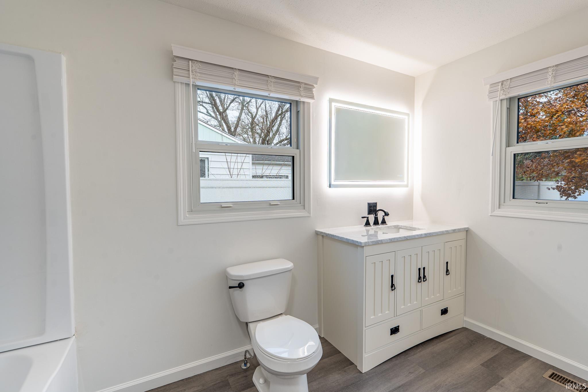 Full bath with vanity and dark wood-style floors