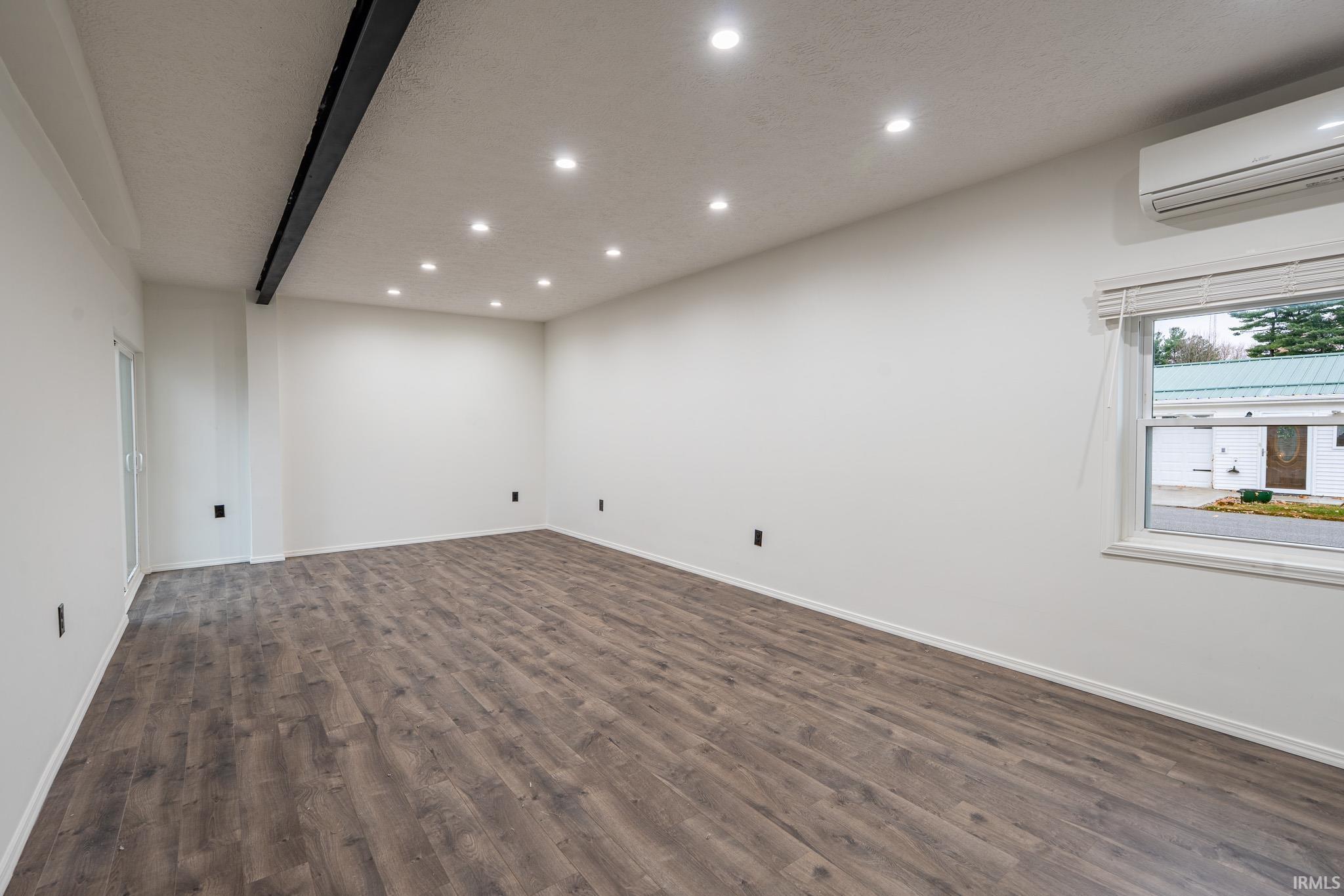 Spare room with recessed lighting, dark wood-type flooring, a wall mounted AC, and a textured ceiling