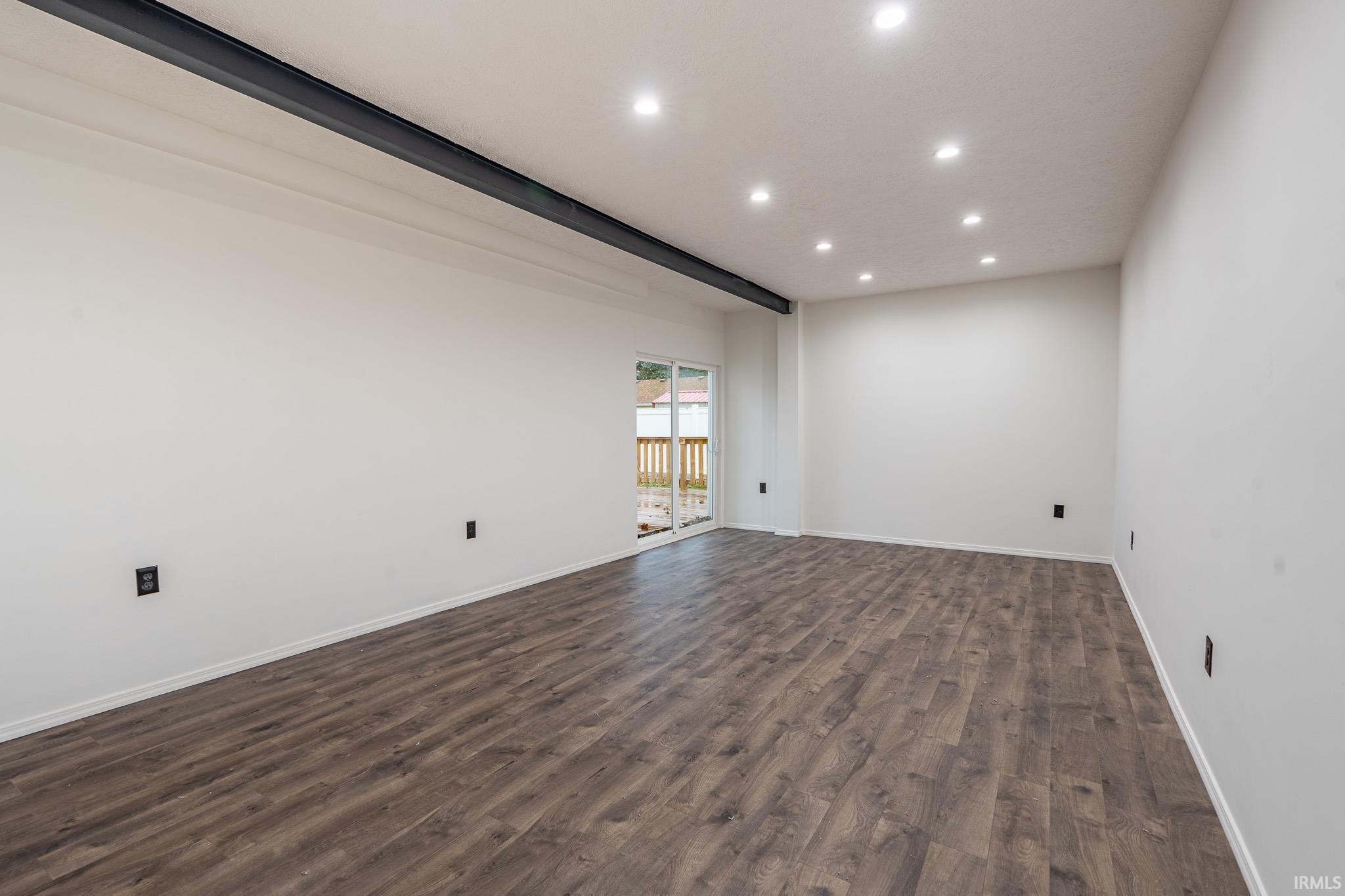 Empty room featuring recessed lighting, dark wood-type flooring, and beam ceiling