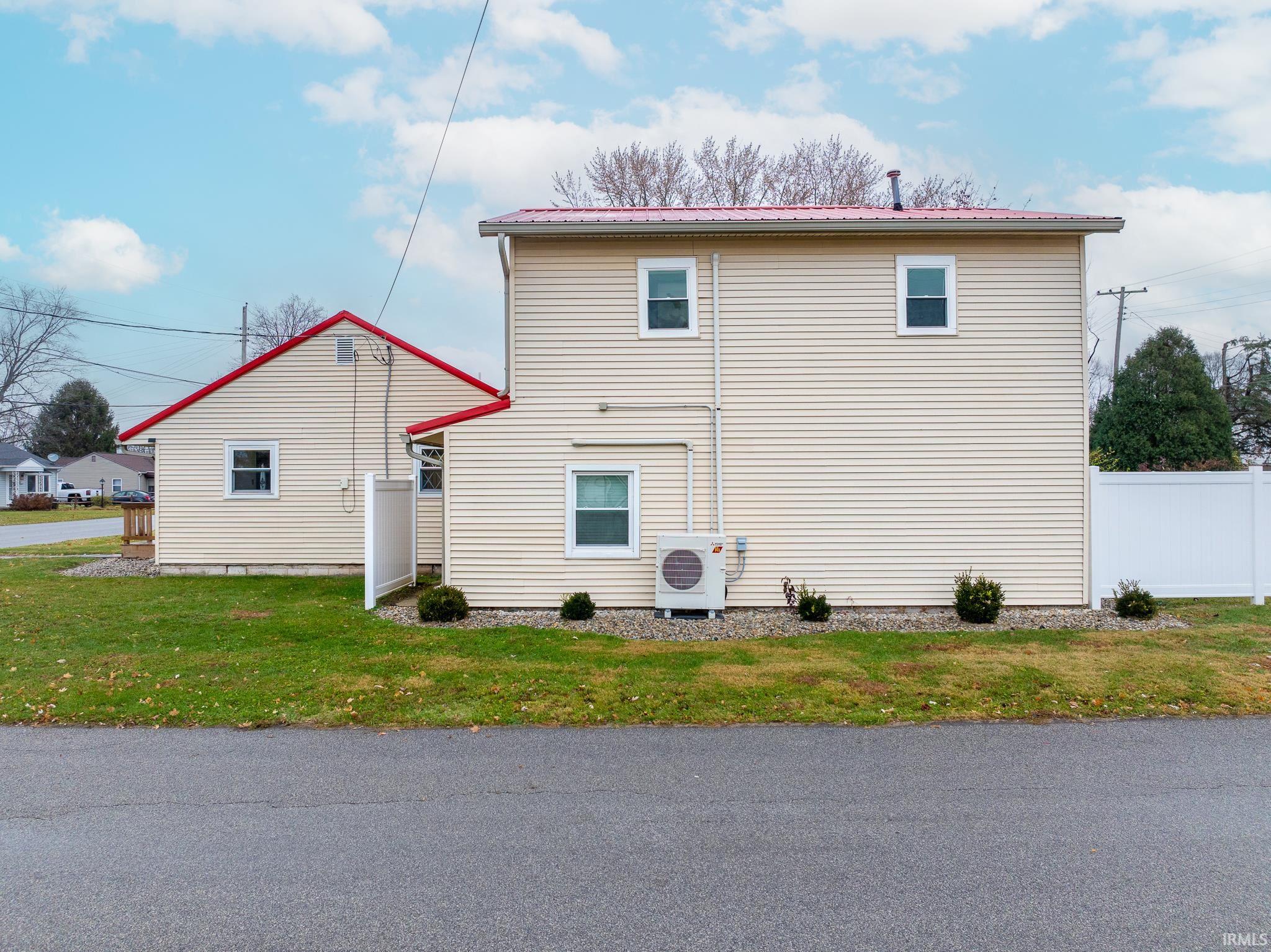 View of side of property with an ac unit and a metal roof