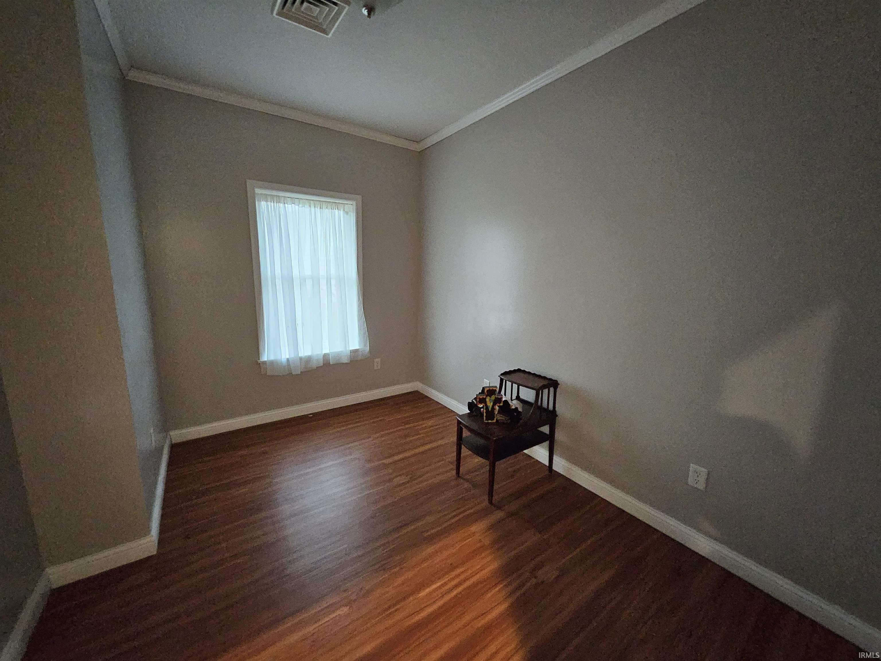 Unfurnished room with crown molding and dark wood-style flooring