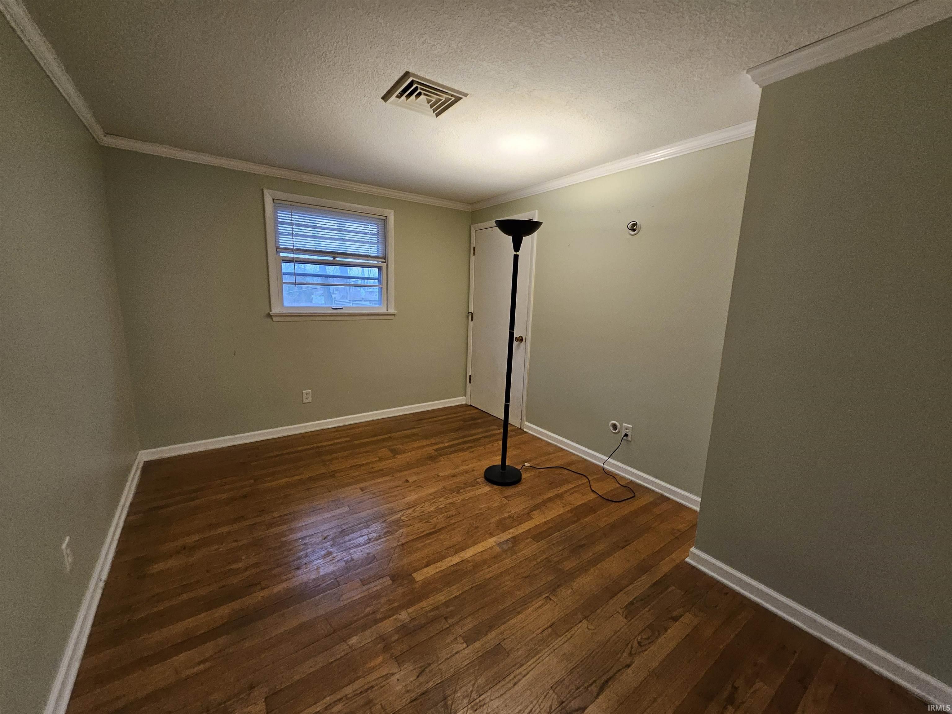 Spare room with a textured ceiling, dark wood-style floors, and ornamental molding