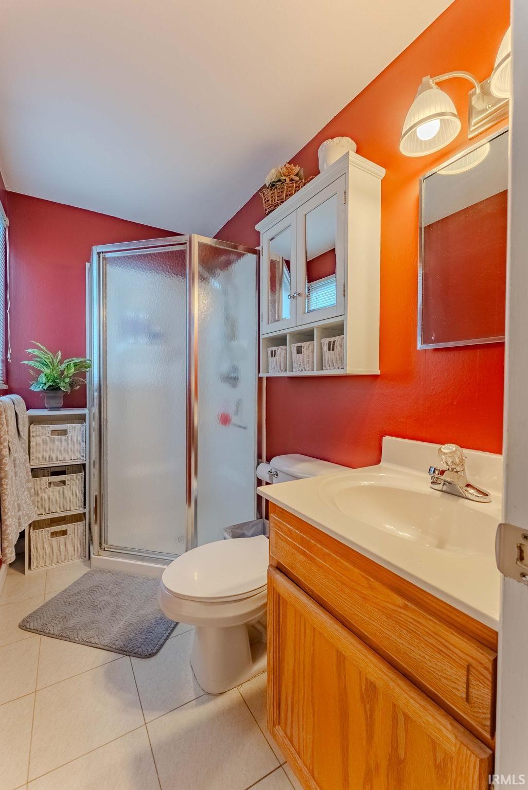Bathroom featuring a stall shower, vanity, and light tile patterned flooring