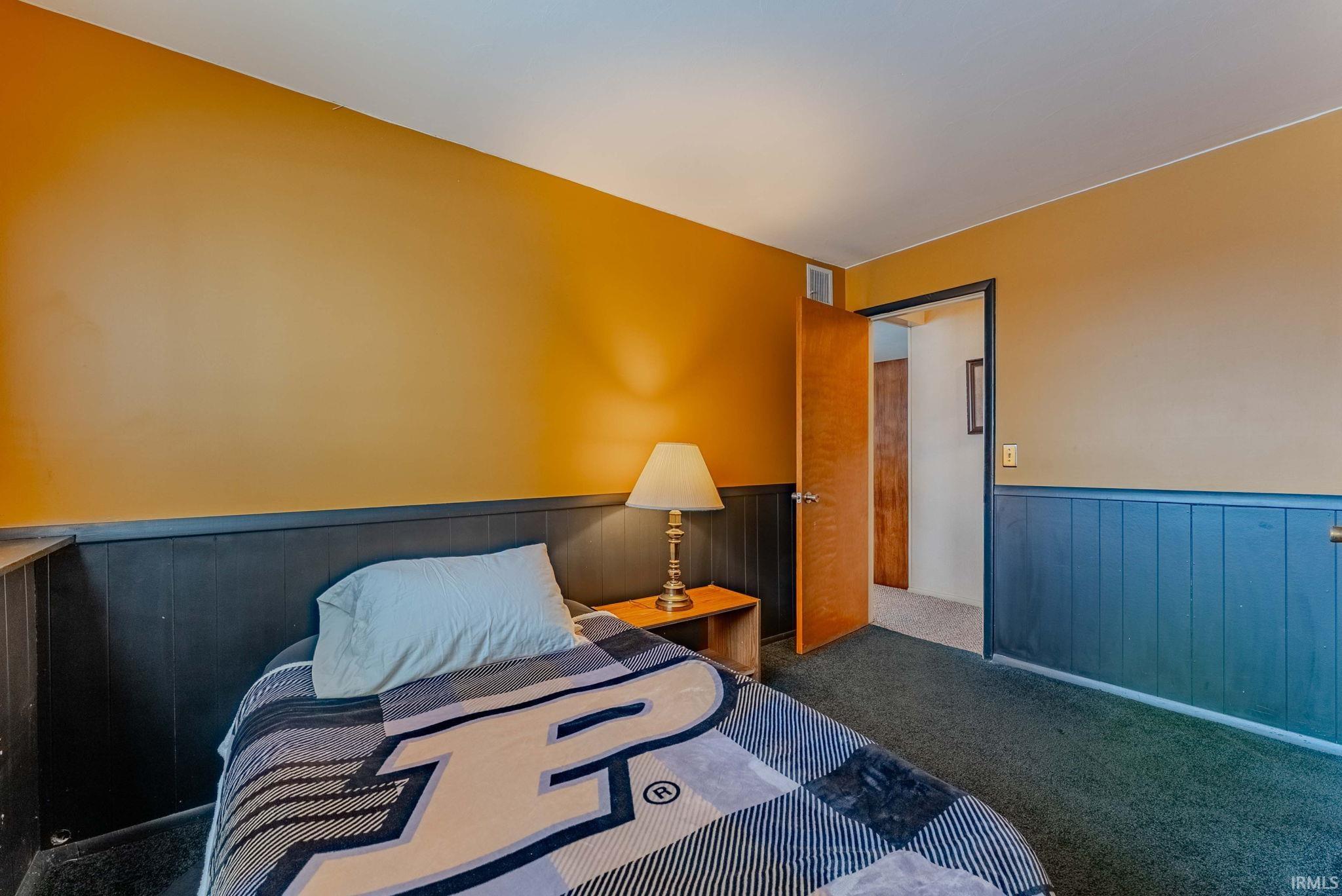 Bedroom featuring a wainscoted wall and carpet flooring
