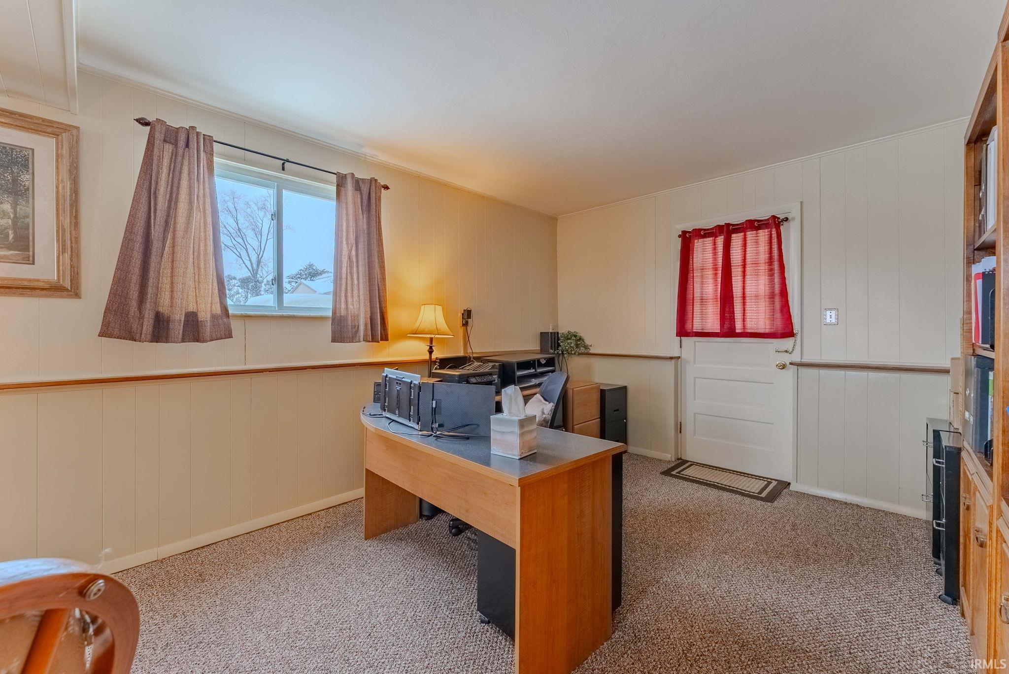 Carpeted office featuring wood walls and crown molding