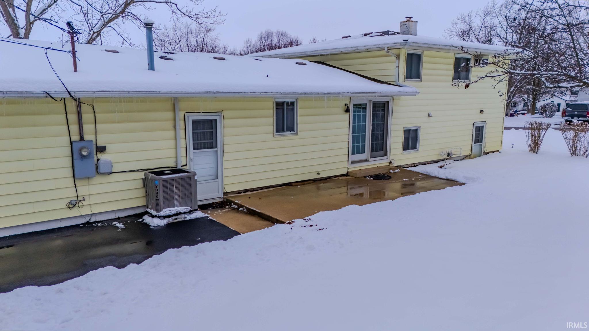 Snow covered rear of property with a patio area and a chimney