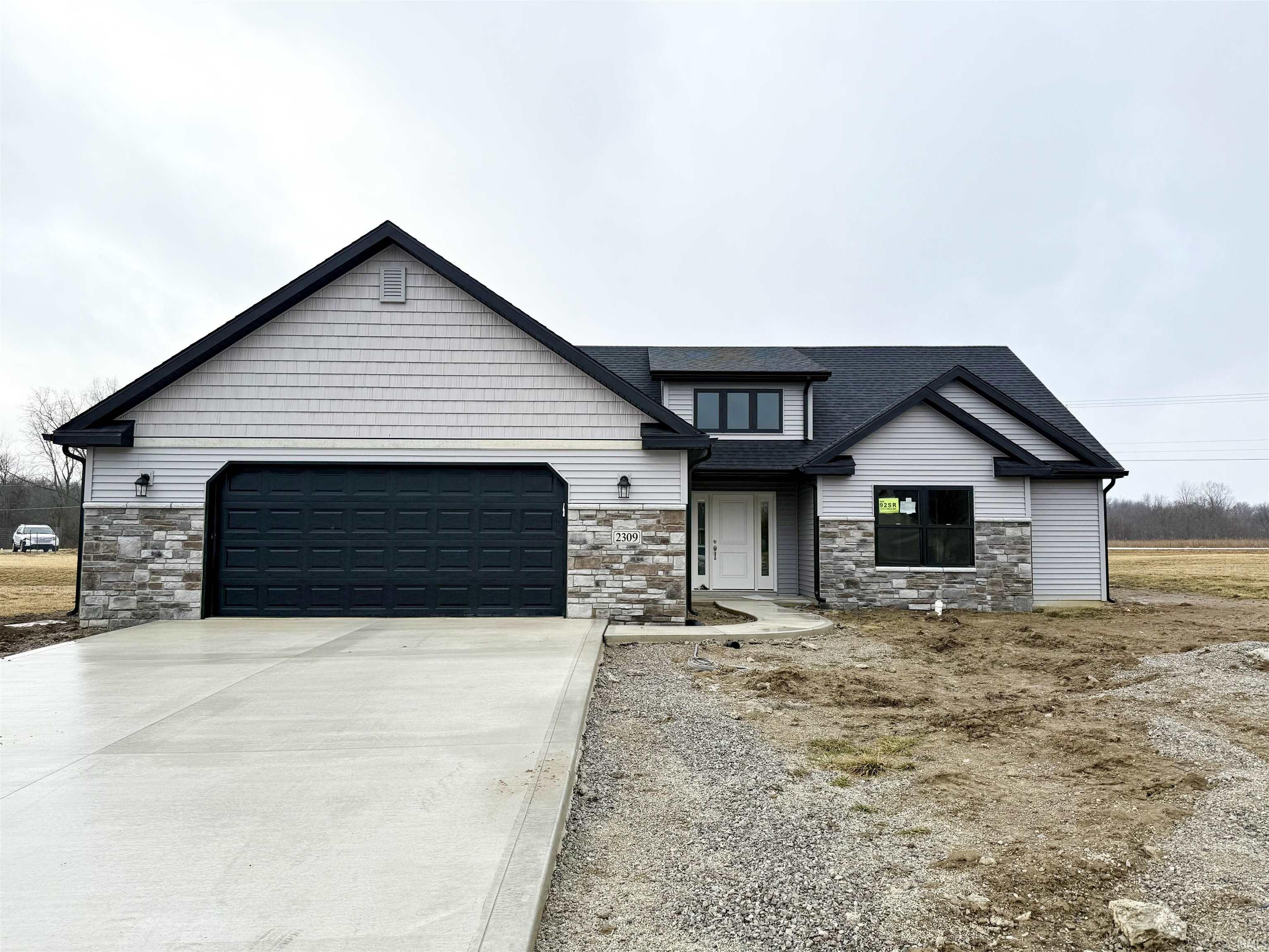 View of front of house with stone siding, concrete driveway, an attached garage, and roof with shingles
