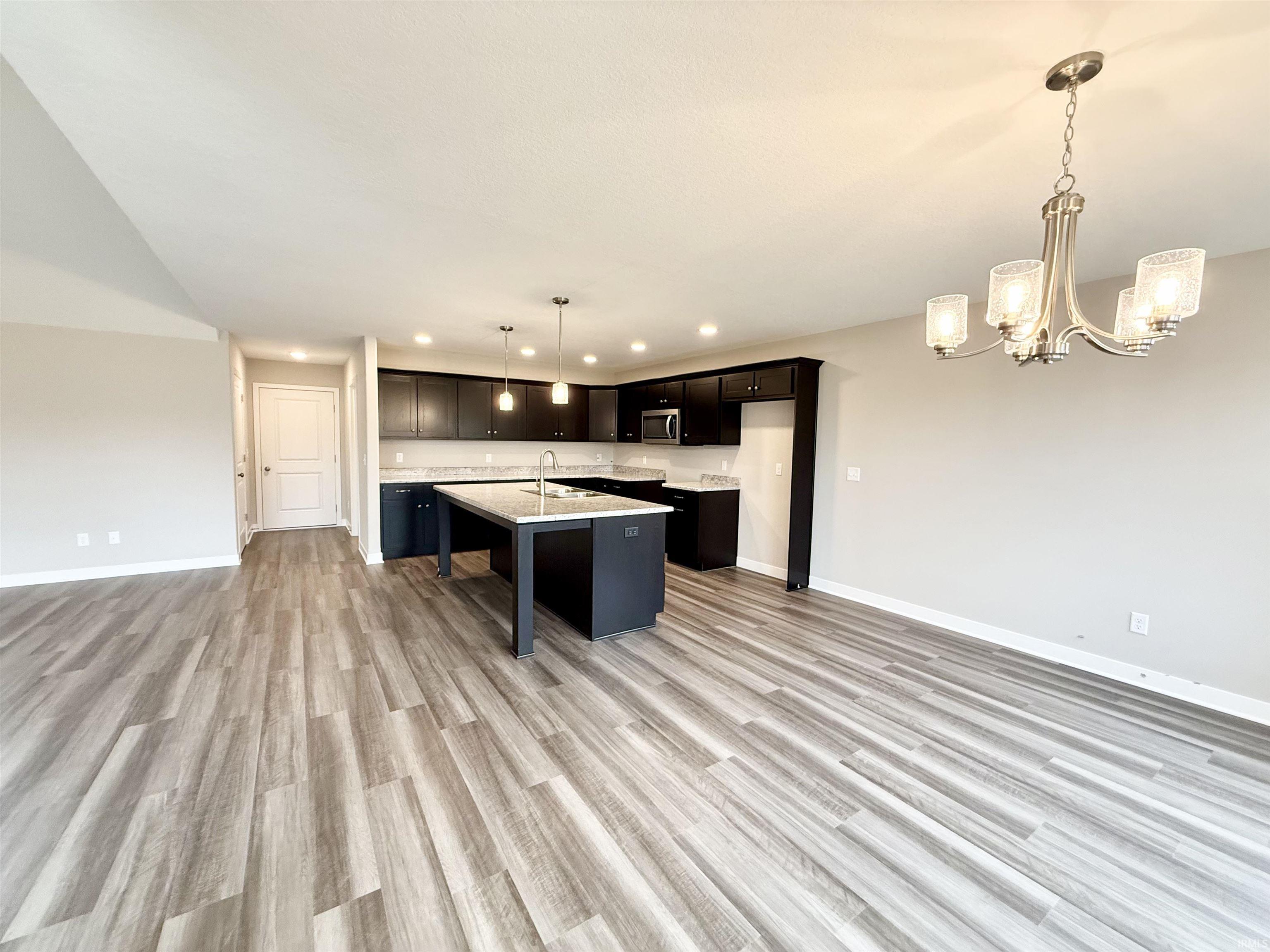 Kitchen featuring a breakfast bar, open floor plan, a chandelier, and a kitchen island with sink