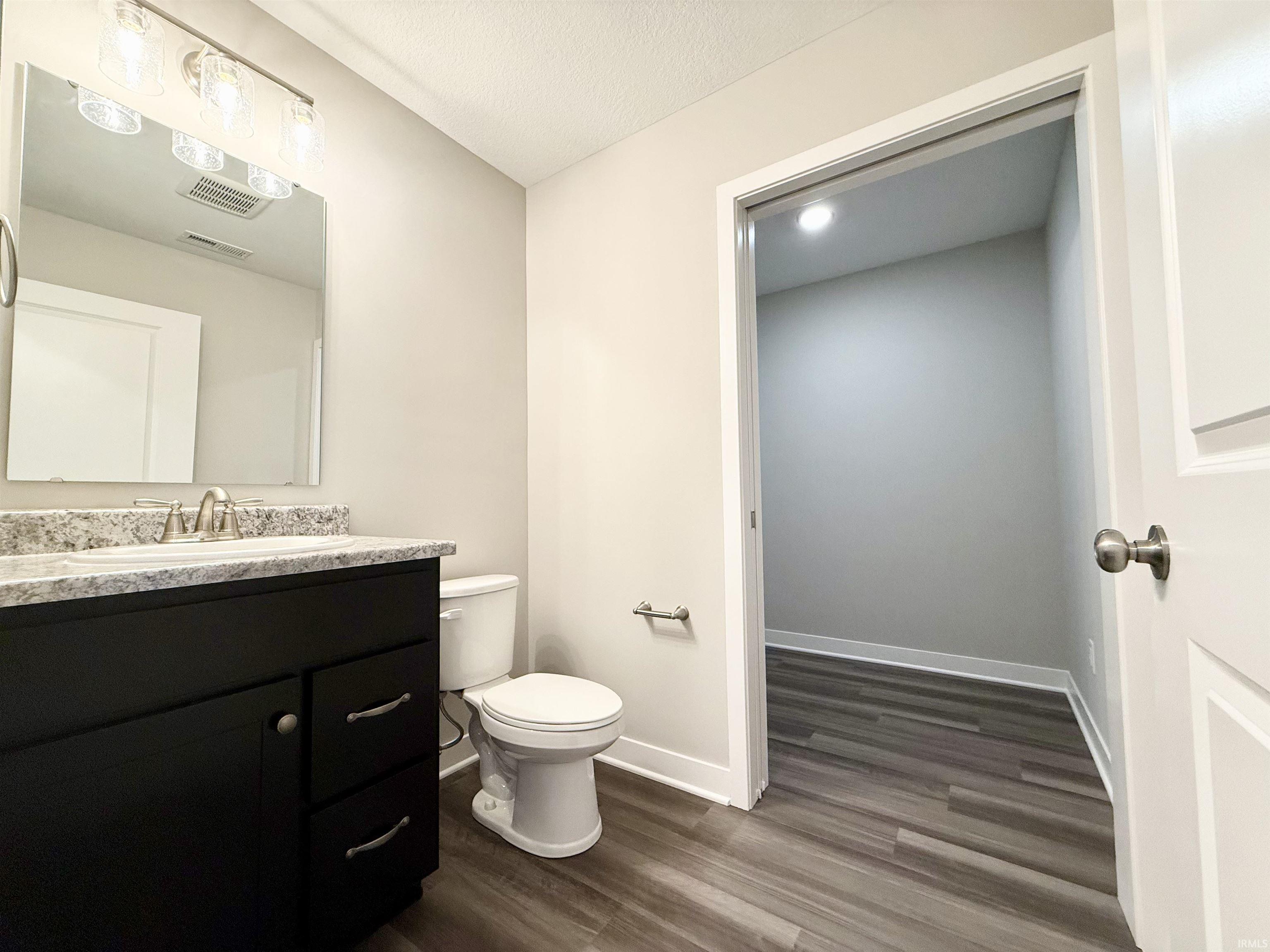 Half bathroom with vanity and dark wood-style floors