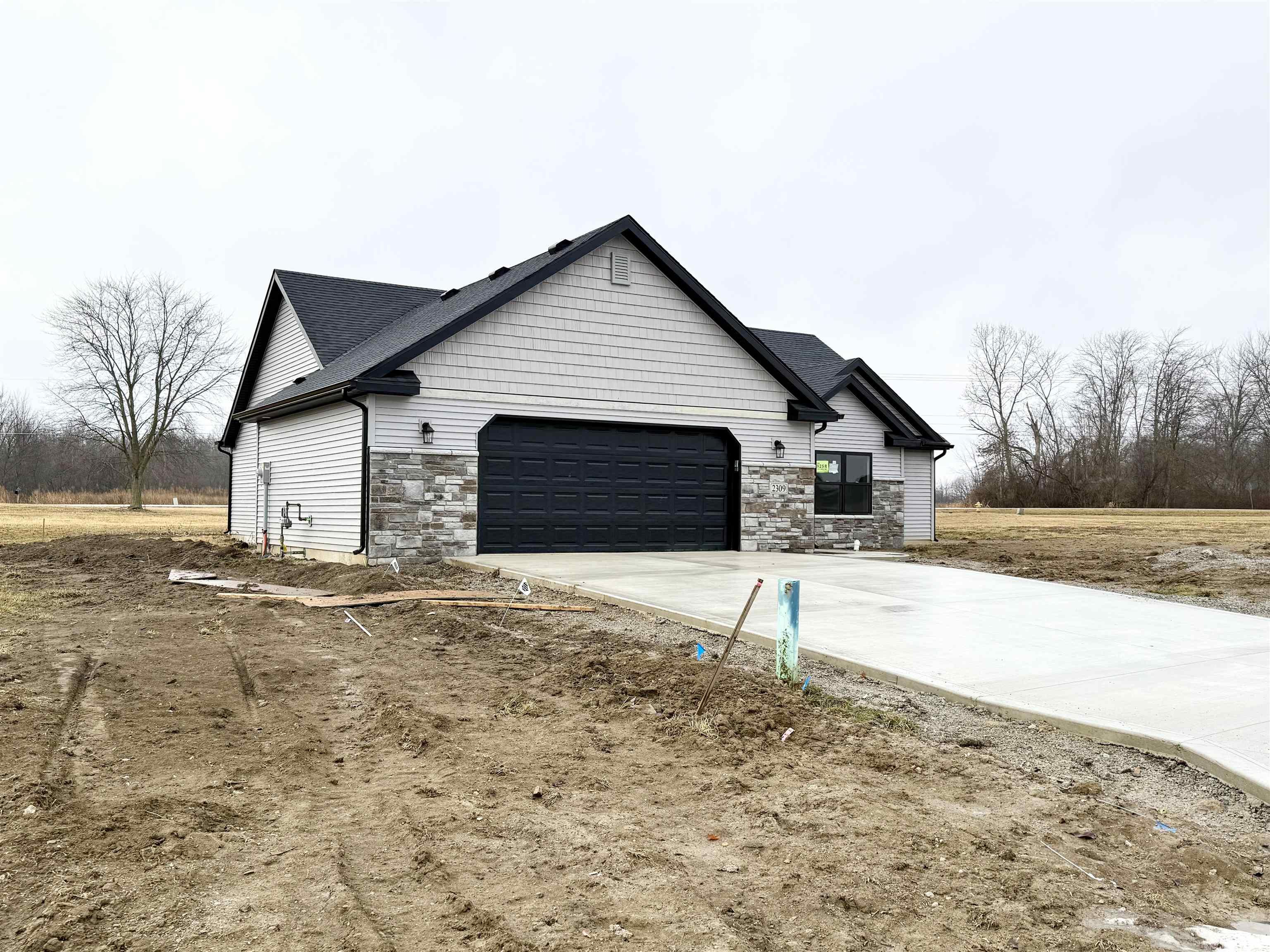 View of property exterior featuring stone siding, concrete driveway, and an attached garage