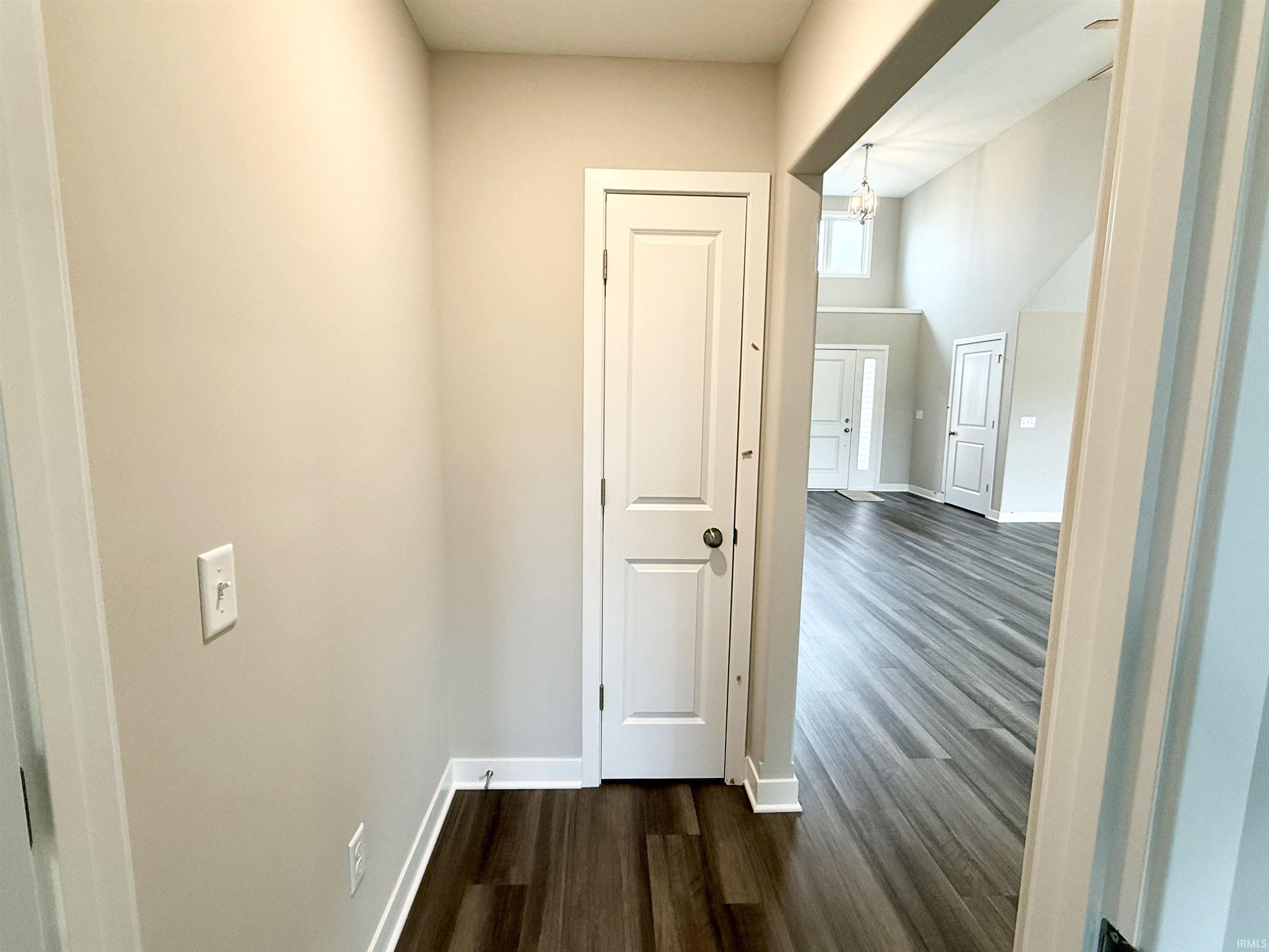 Hallway featuring dark wood-style floors and baseboards