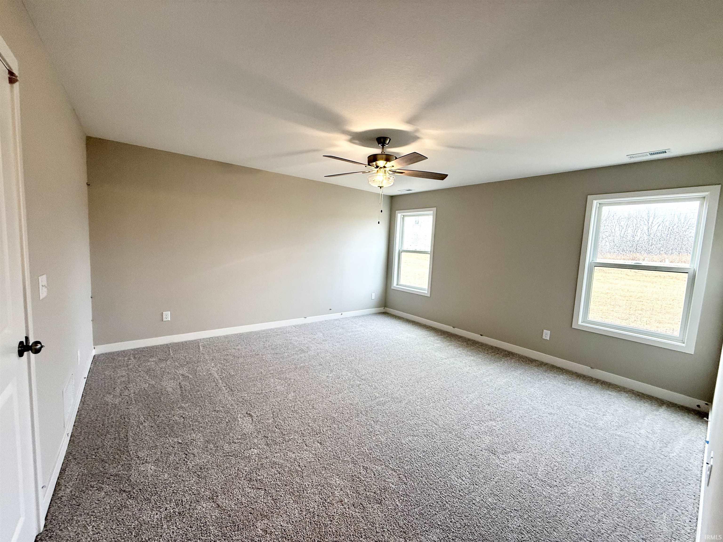 Carpeted spare room featuring baseboards and a ceiling fan