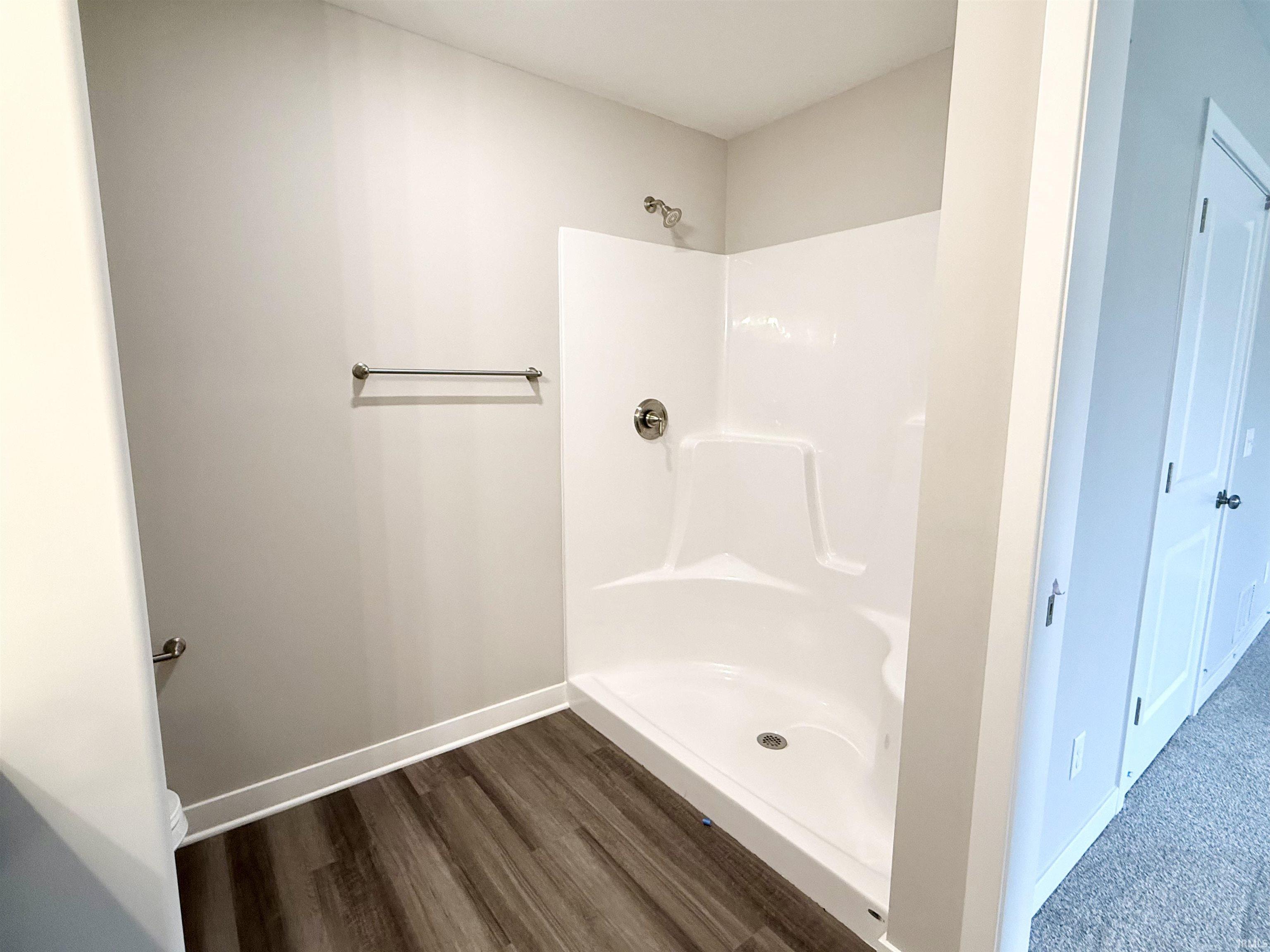 Bathroom with a stall shower and dark wood-type flooring