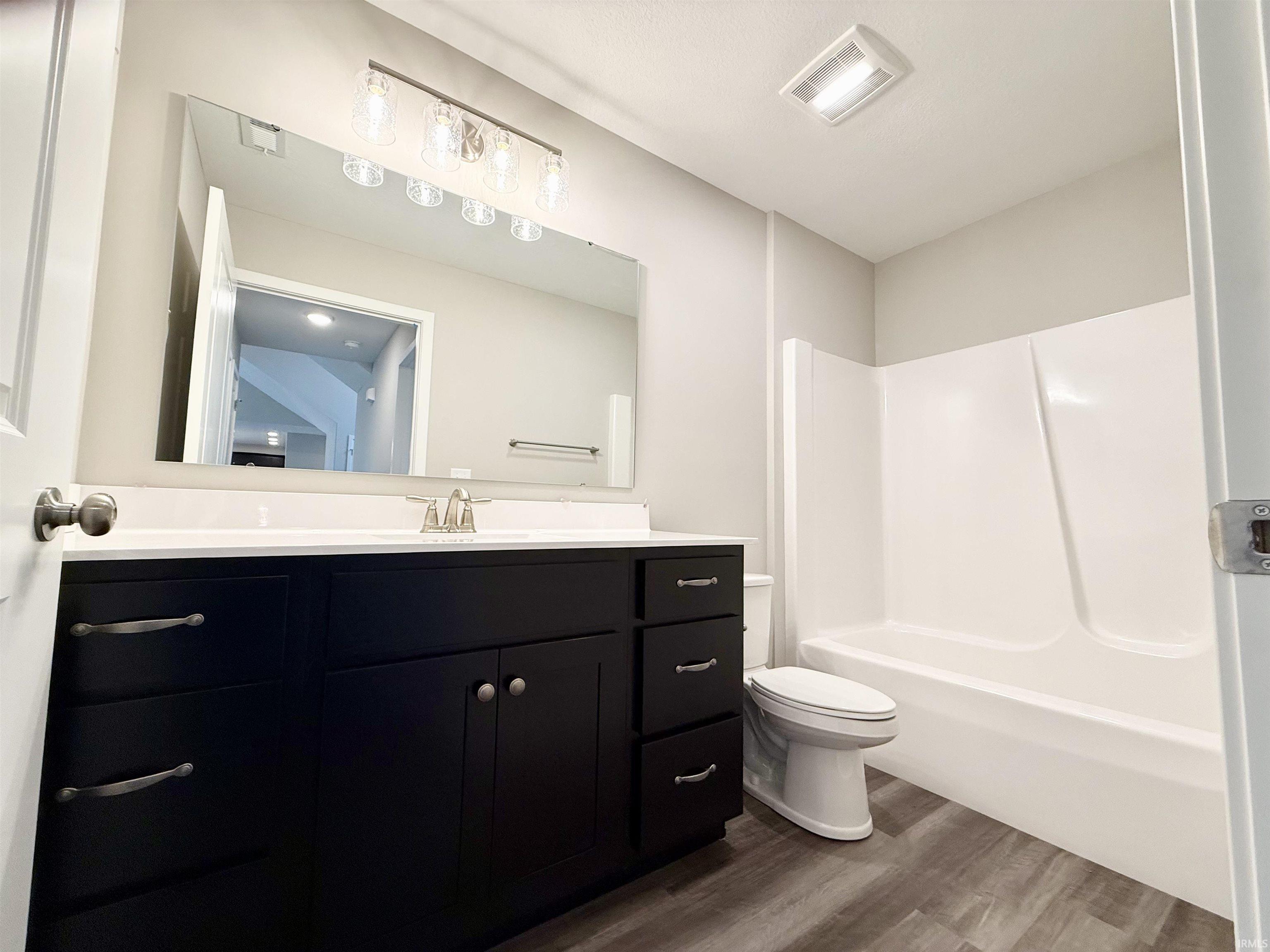 Bathroom with vanity, dark wood-type flooring, and shower / bath combination