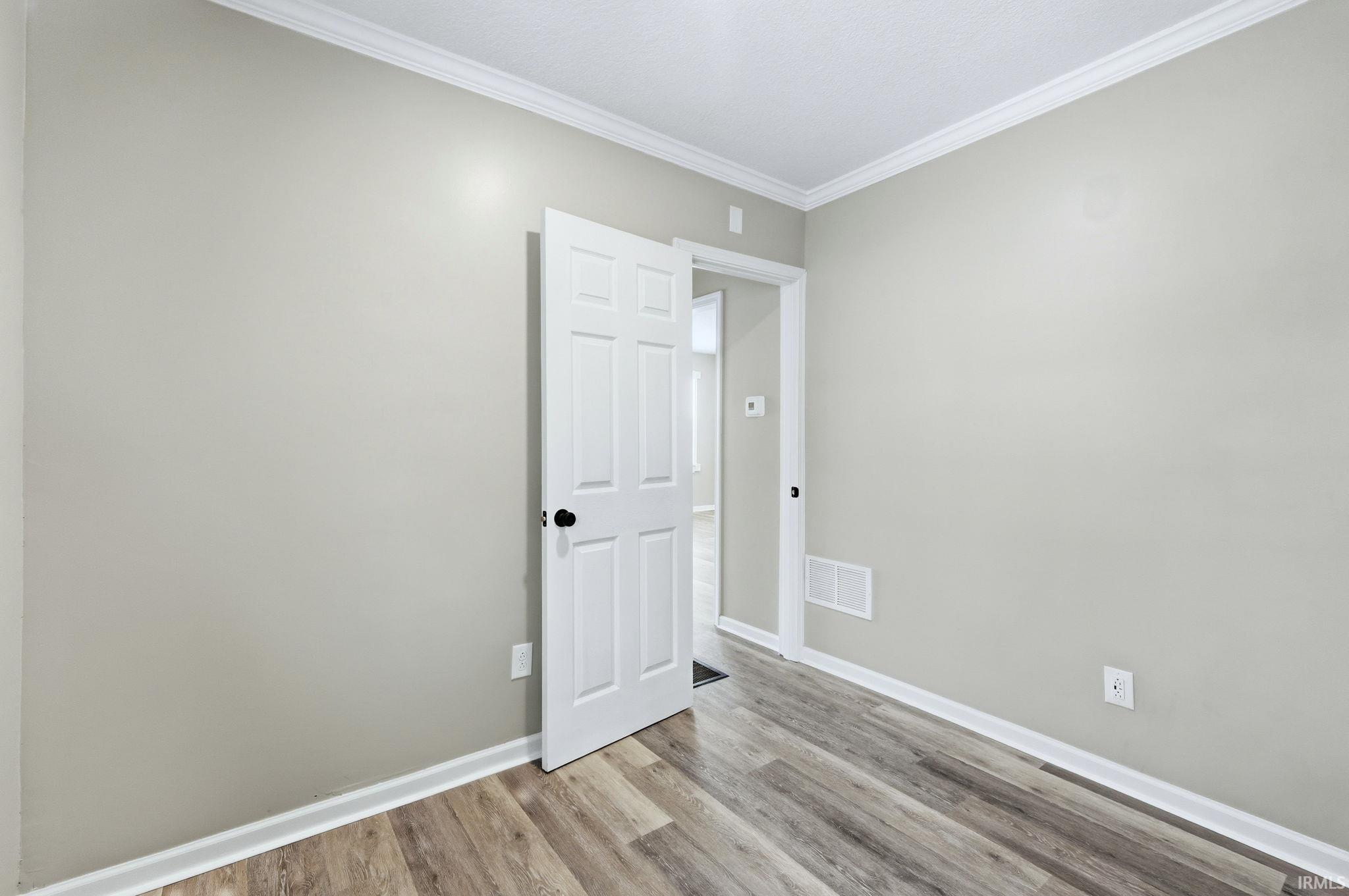 Unfurnished room with crown molding and wood finished floors