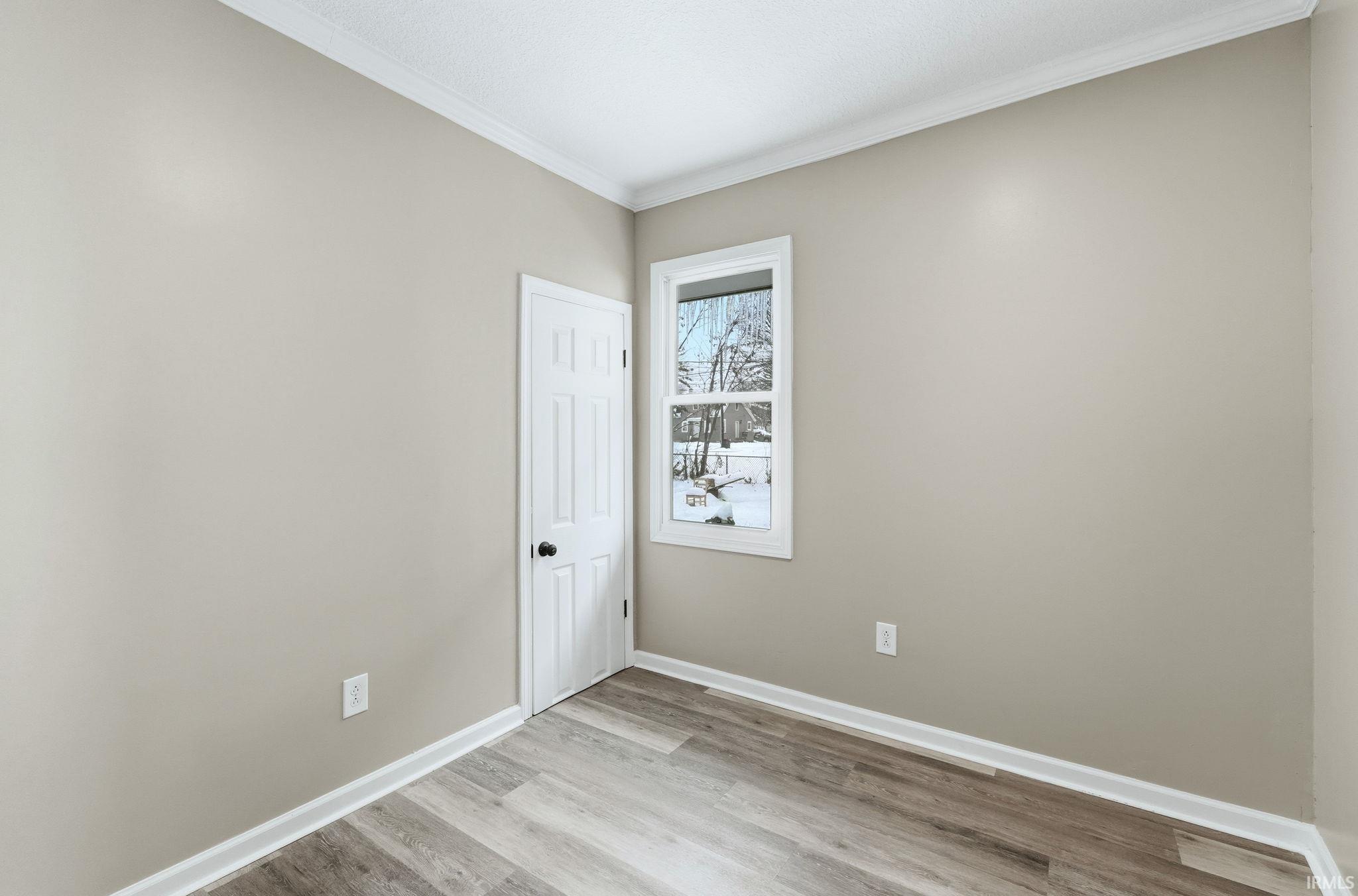 Spare room with crown molding and light wood-style floors