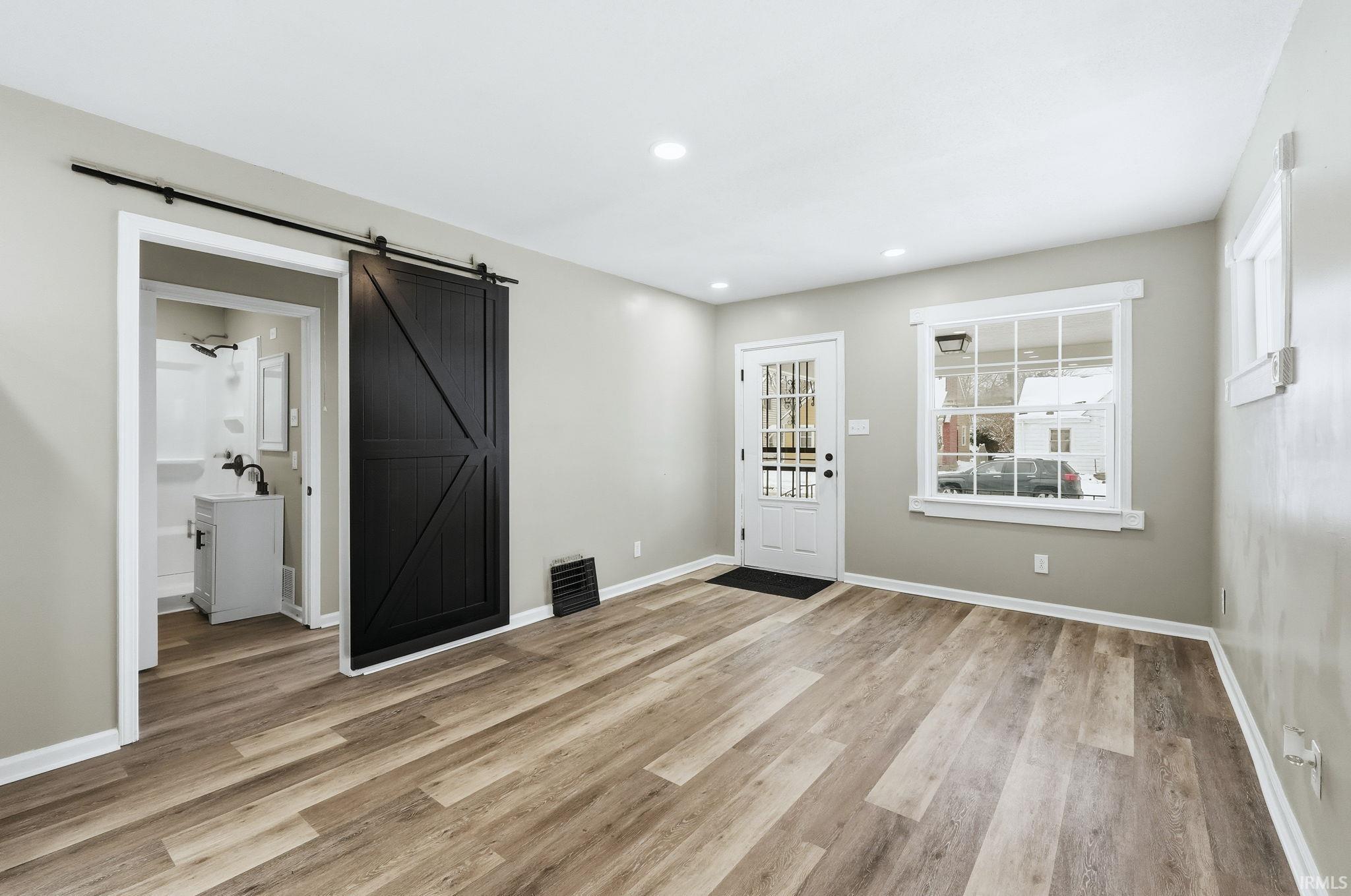Entryway featuring a barn door, light wood finished floors, and recessed lighting