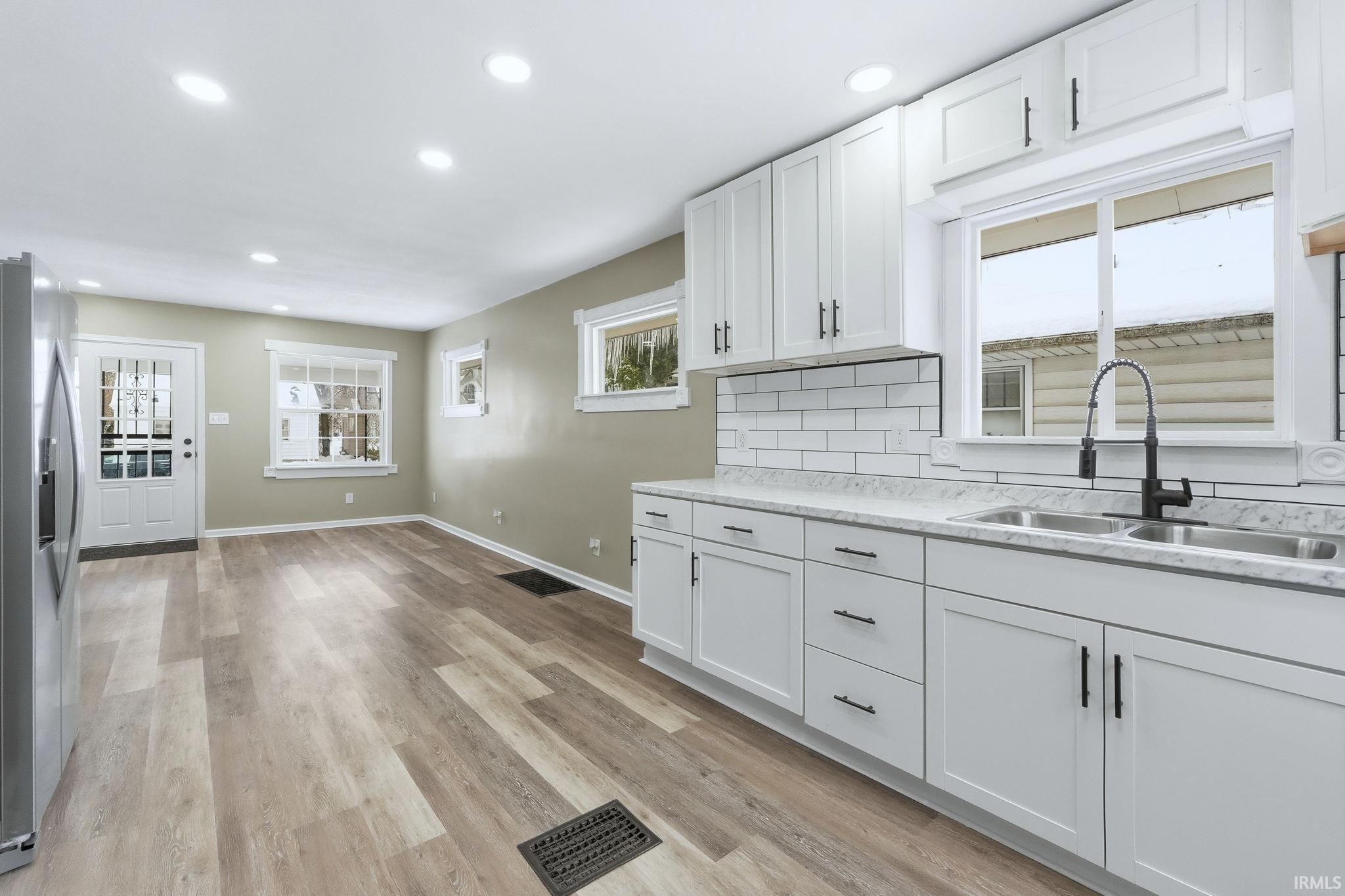 Kitchen featuring white cabinets, tasteful backsplash, stainless steel fridge, recessed lighting, and plenty of natural light