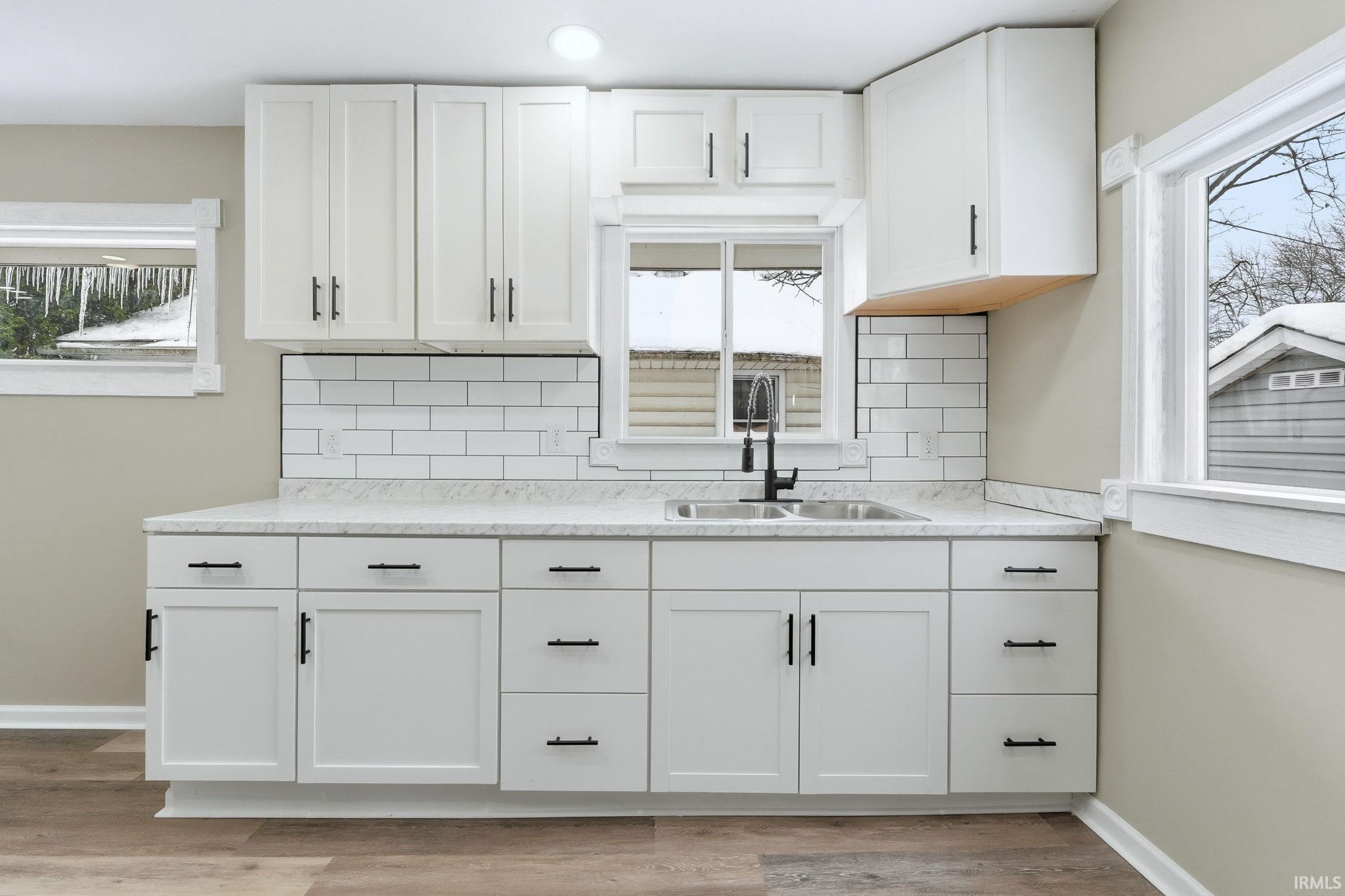 Kitchen with tasteful backsplash and white cabinetry