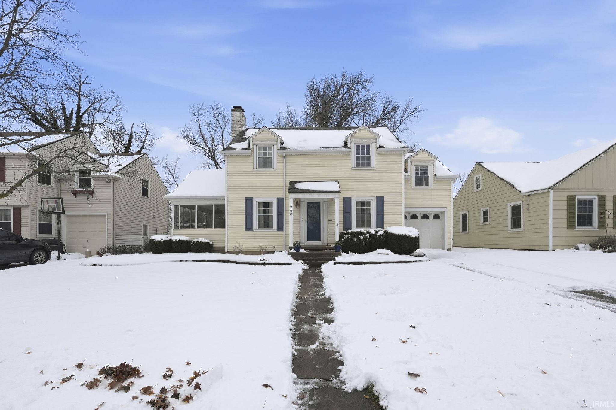 Snow covered property with a chimney and a sunroom