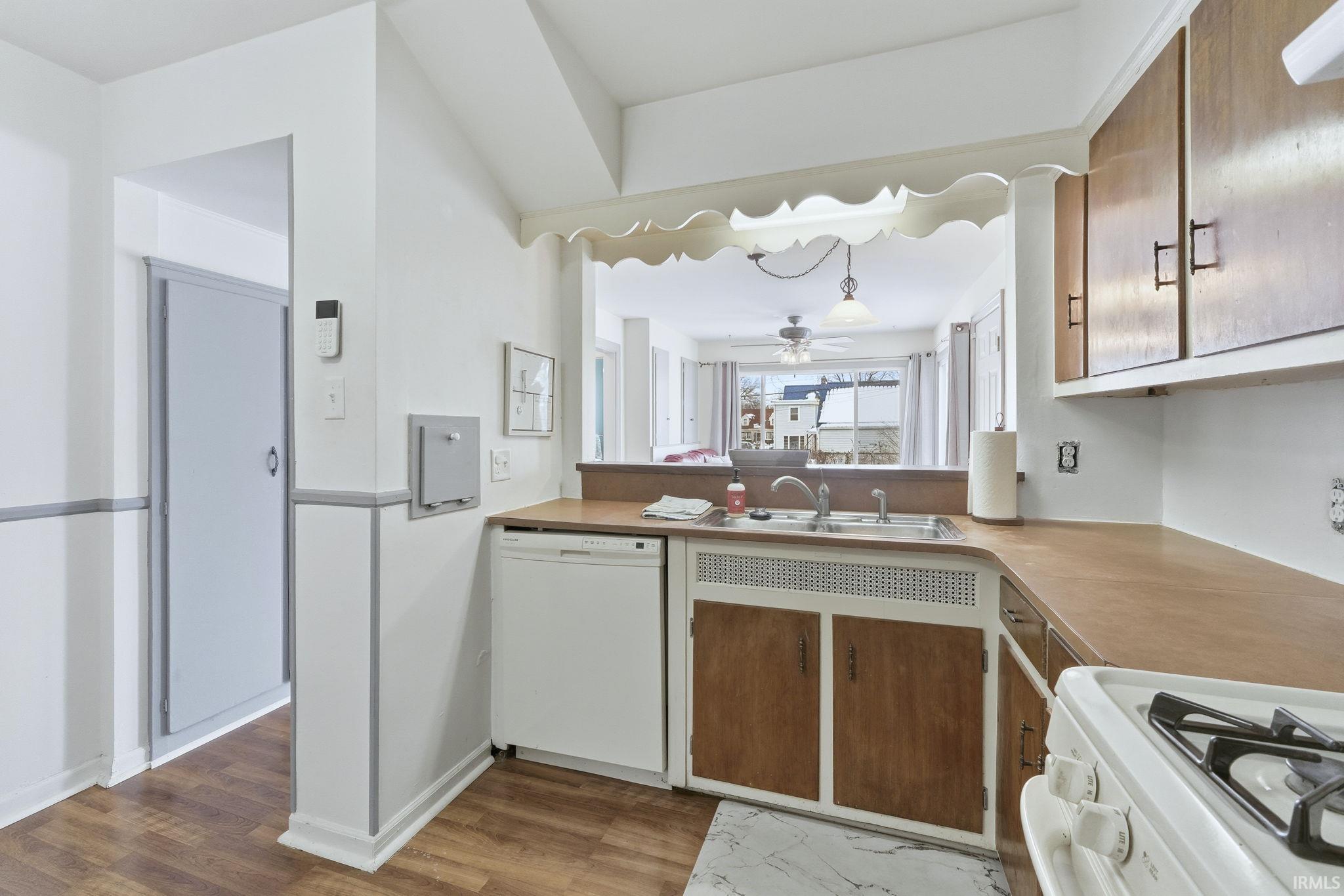 Kitchen with white appliances, light countertops, light wood-type flooring, and brown cabinetry