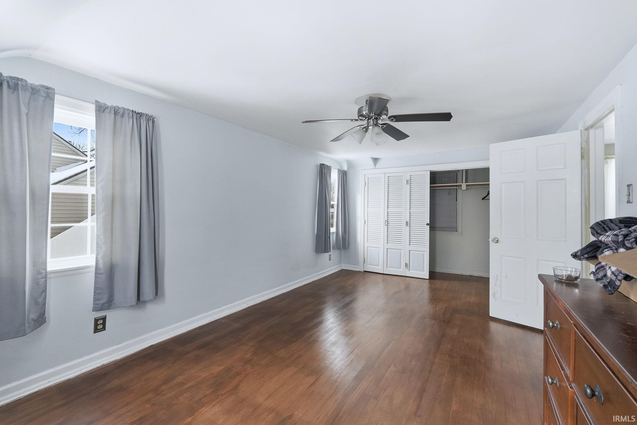 Unfurnished bedroom featuring a closet, dark wood-style floors, and a ceiling fan