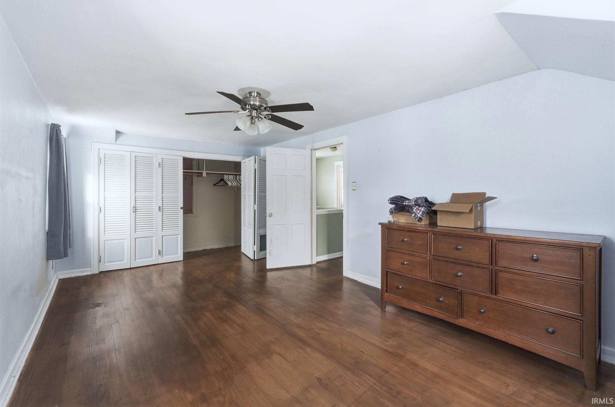 Bedroom featuring a closet, dark wood-style floors, and ceiling fan