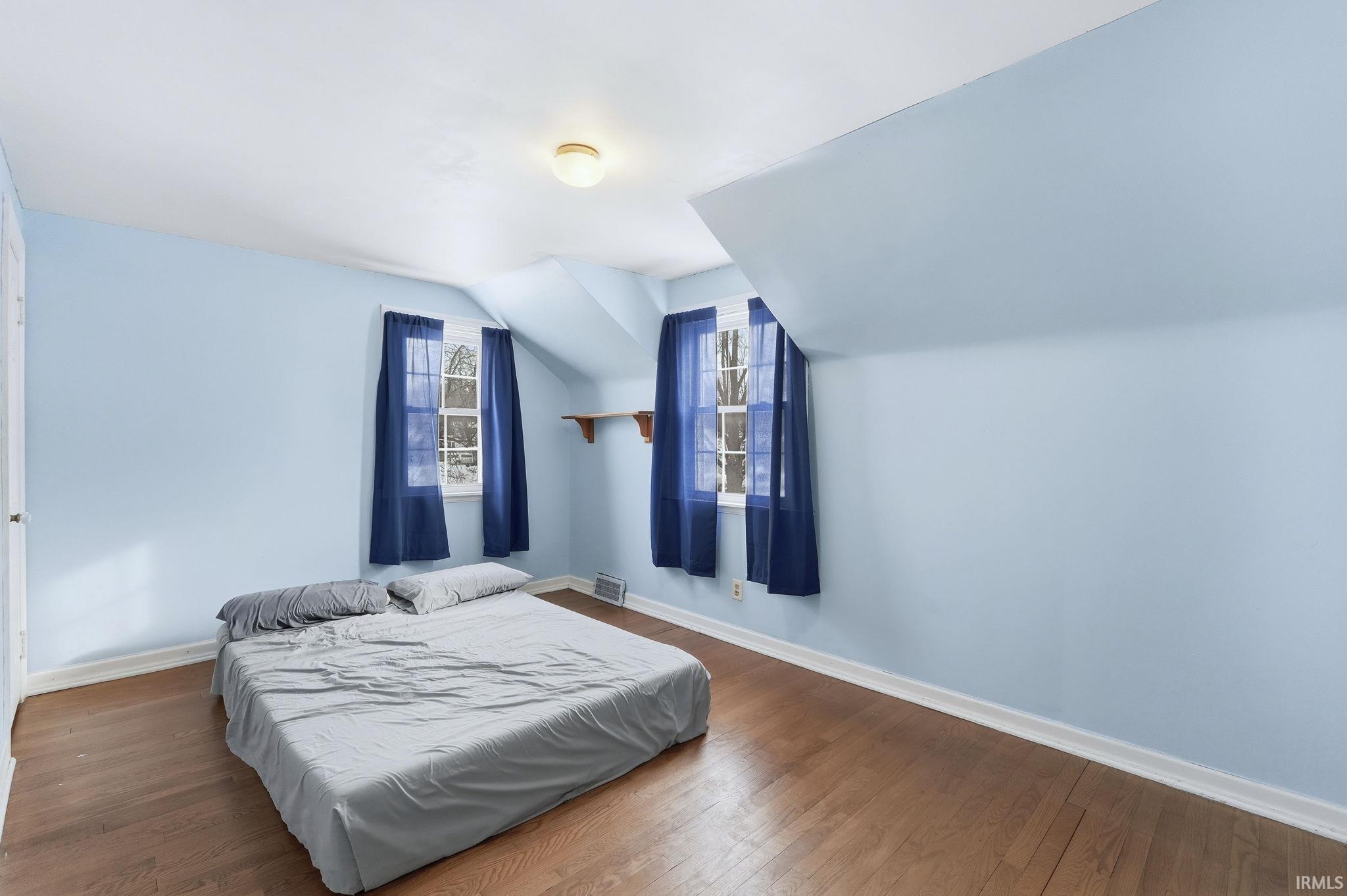 Bedroom with vaulted ceiling and wood finished floors