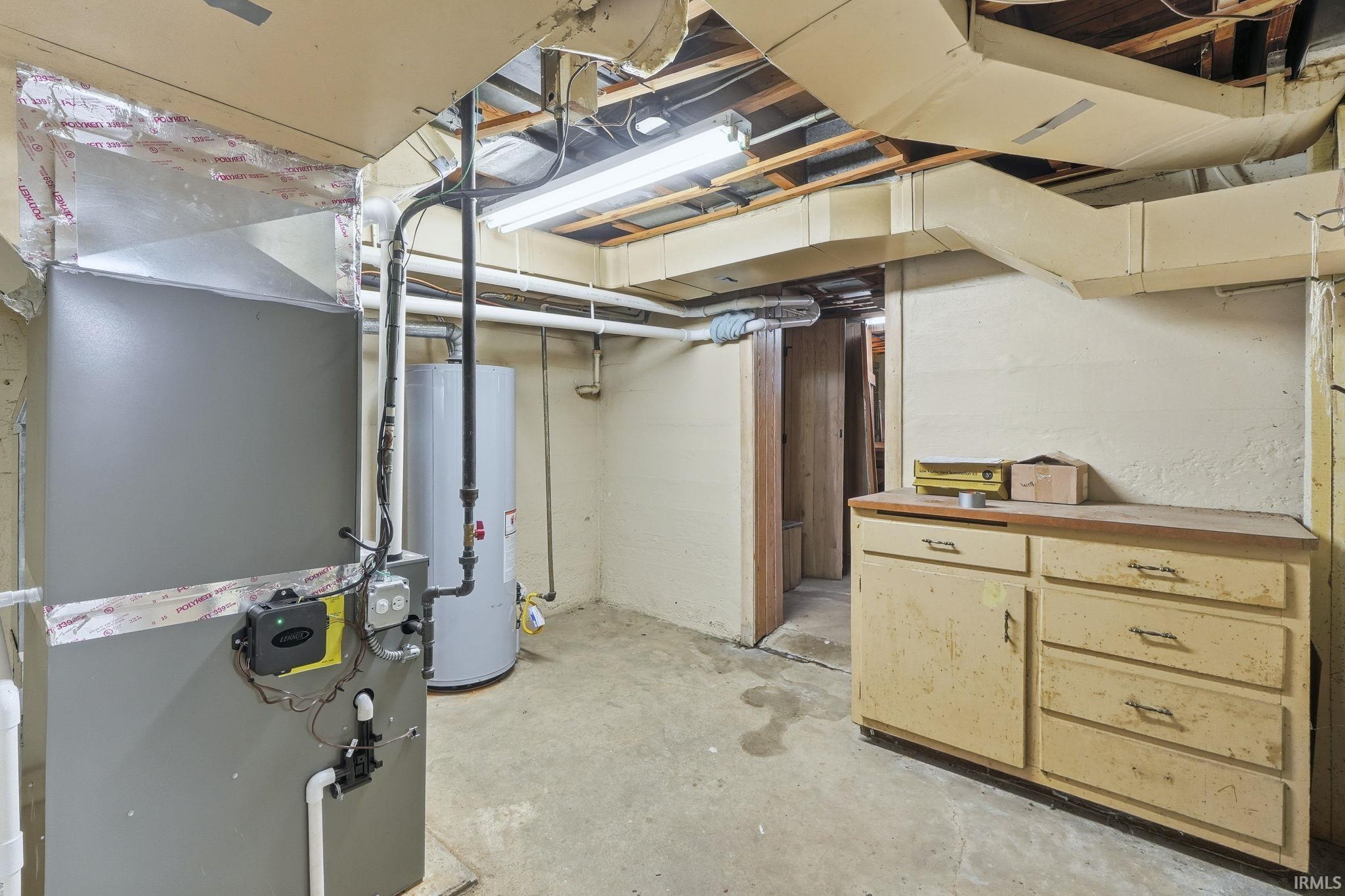 Unfinished below grade area featuring heating unit and water heater