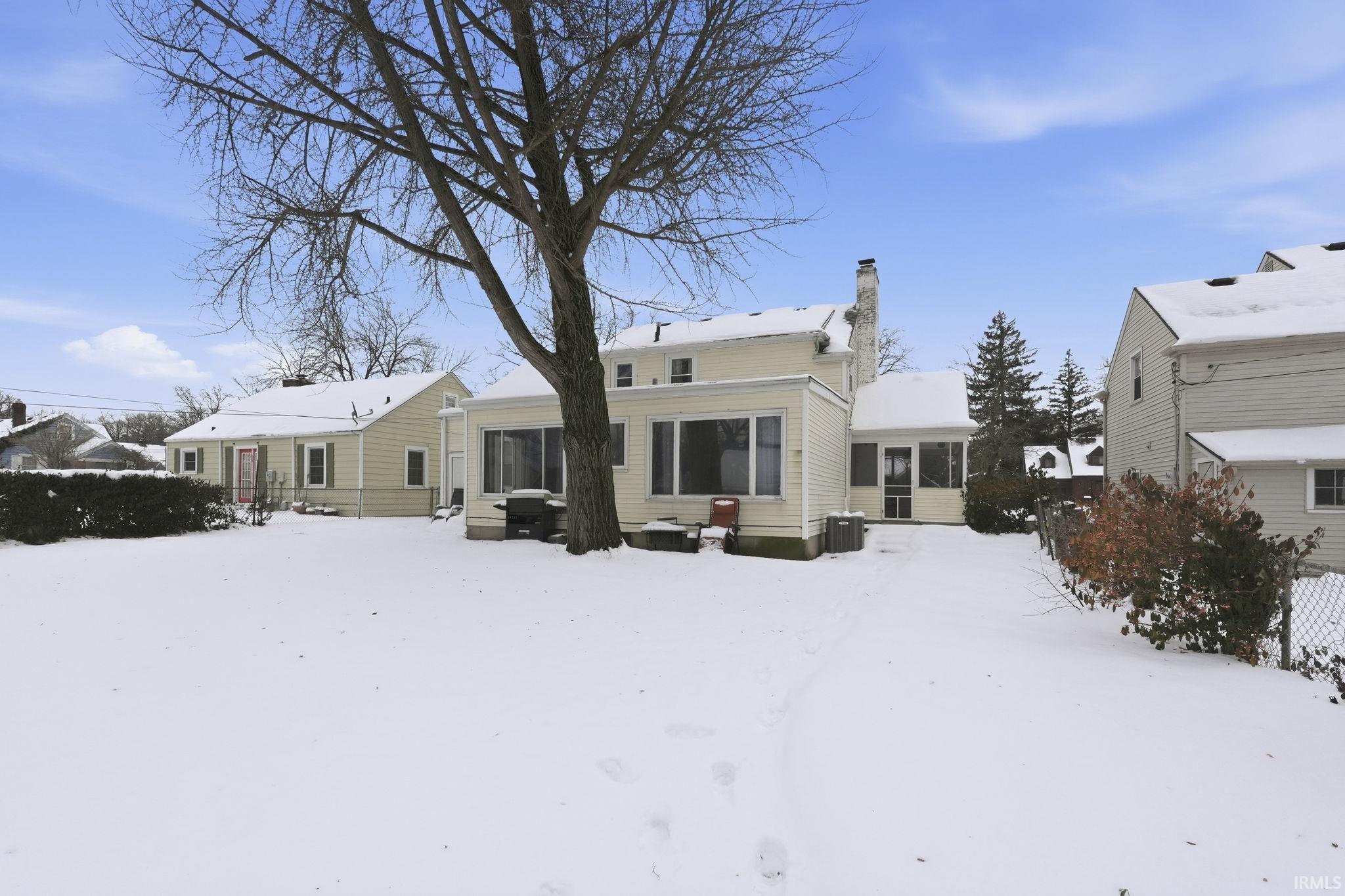 Snow covered rear of property featuring a chimney