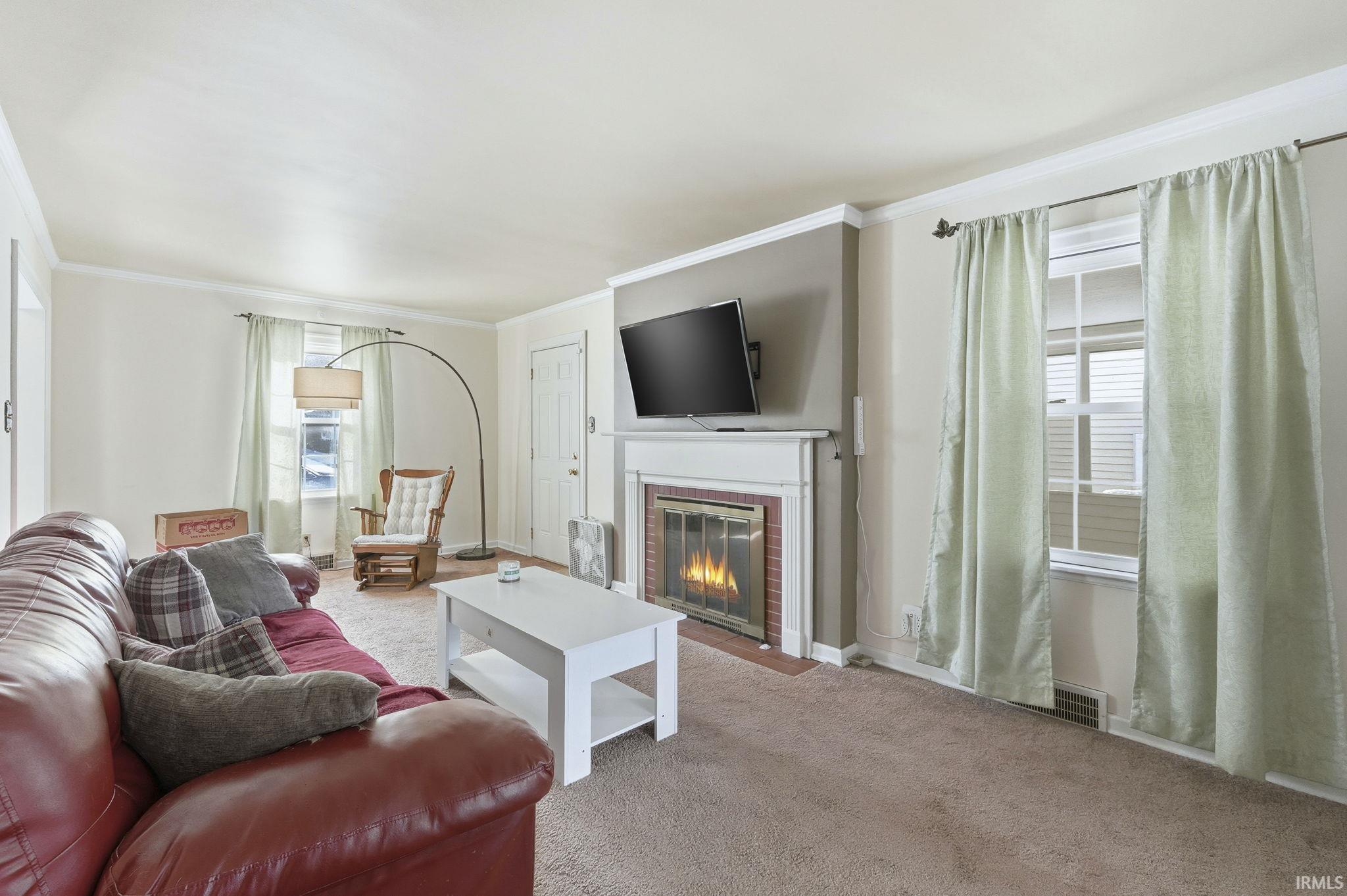 Living room with carpet floors, a fireplace, and ornamental molding