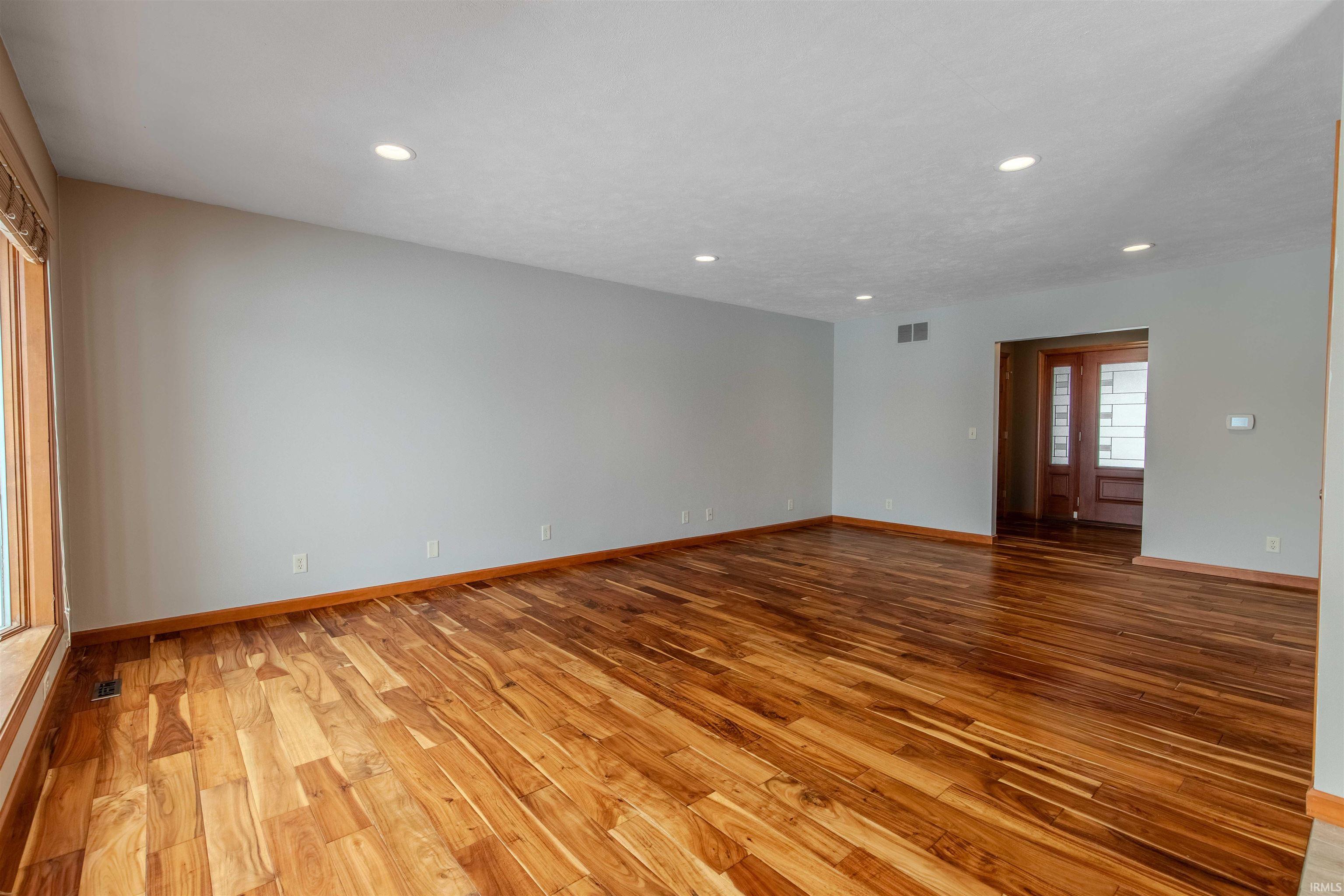 Empty room with light wood-style flooring and recessed lighting
