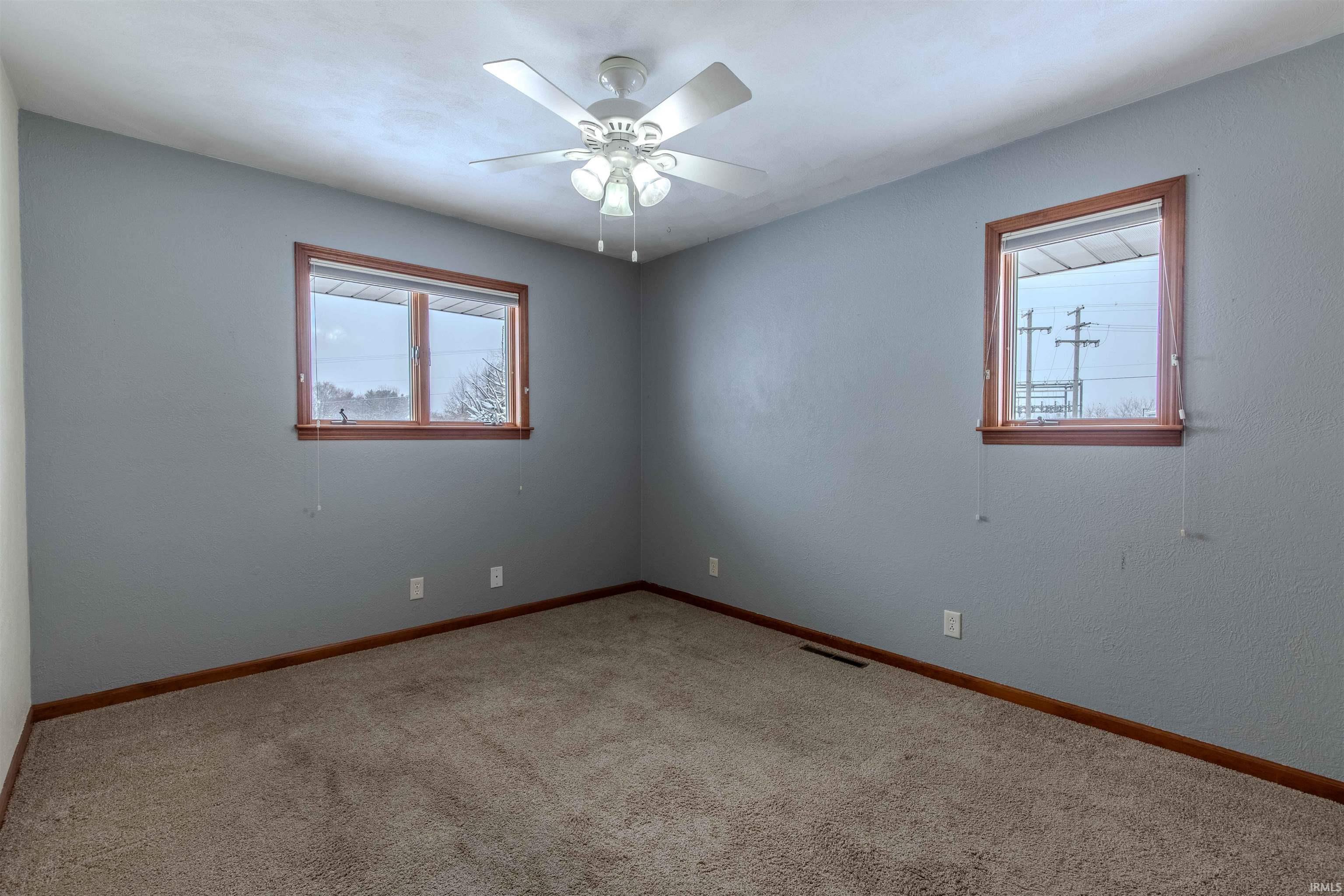 Empty room featuring light carpet, healthy amount of natural light, and a ceiling fan
